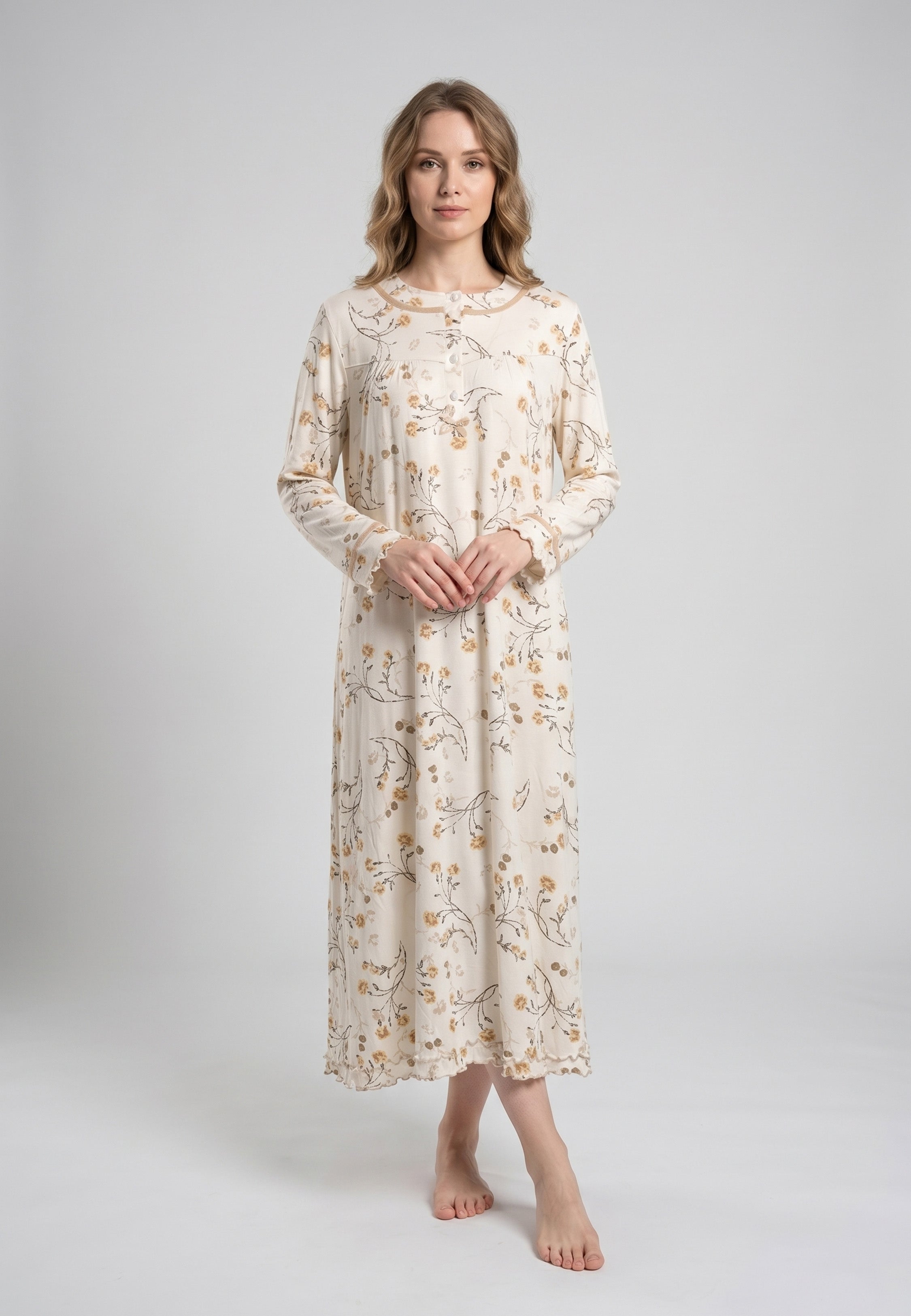 Femme portant une robe de nuit longue col rond boutonné manches longues festonnées imprimé fleuri fleurs sauvages beige et doré sur fond crème Rosabella Soft Bloom