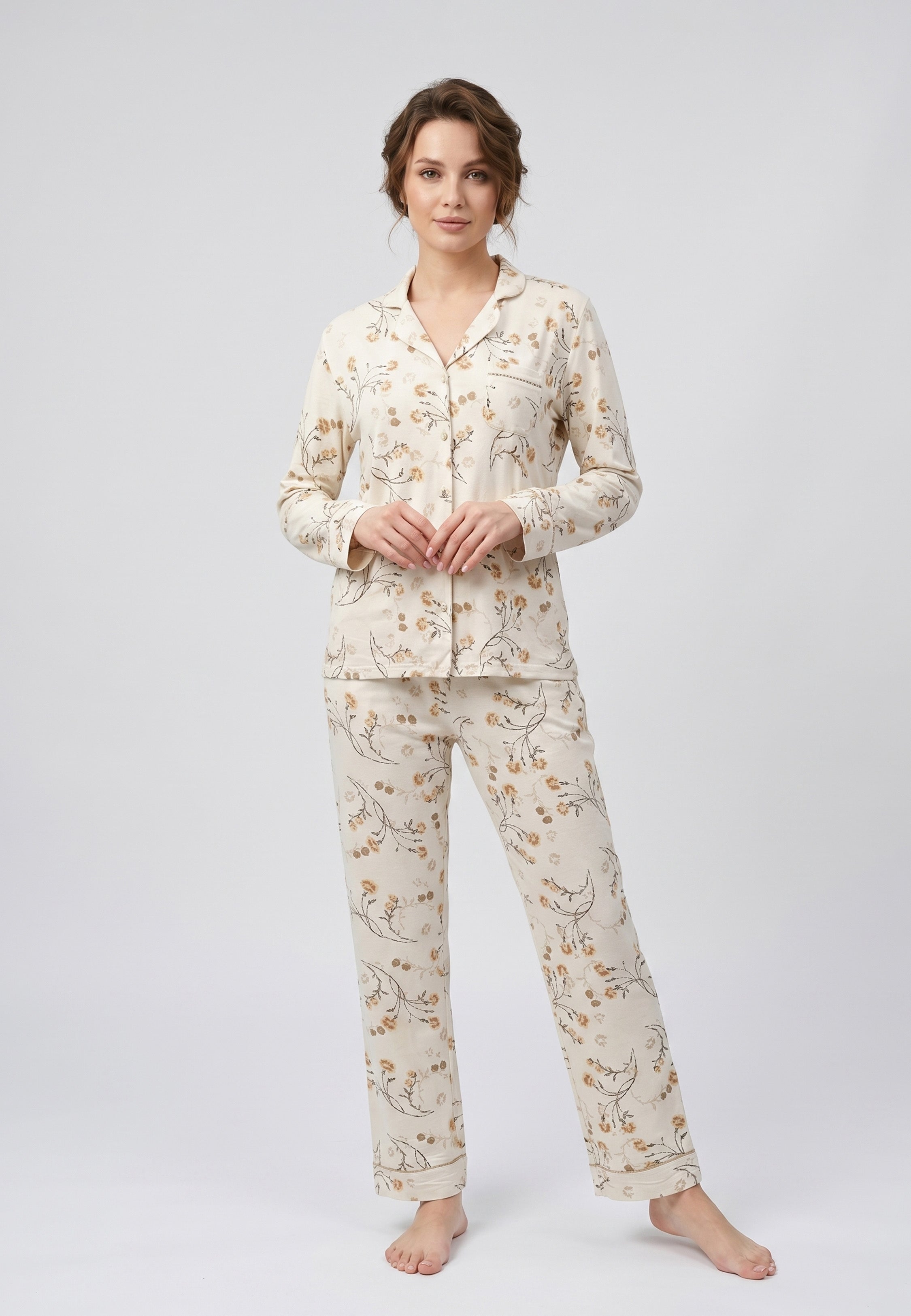 Femme portant un pyjama deux pièces chemise boutonnée col pyjama à revers manches longues poche poitrine imprimé fleuri fleurs sauvages beige et doré sur fond crème et pantalon droit assorti Rosabella Soft Bloom