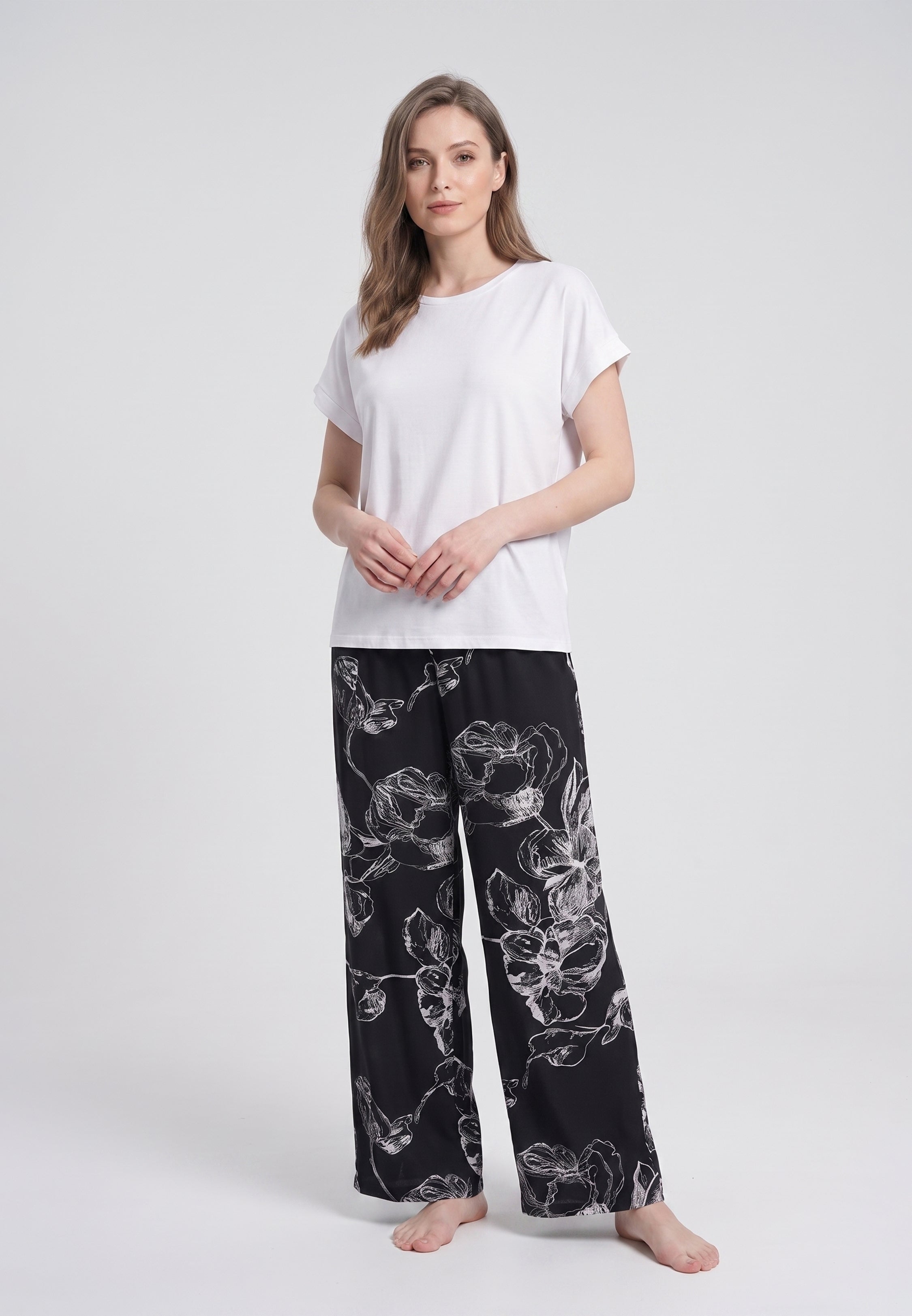 Femme portant un t-shirt écru & pantalon large grandes fleurs écru fond noir Rosabella