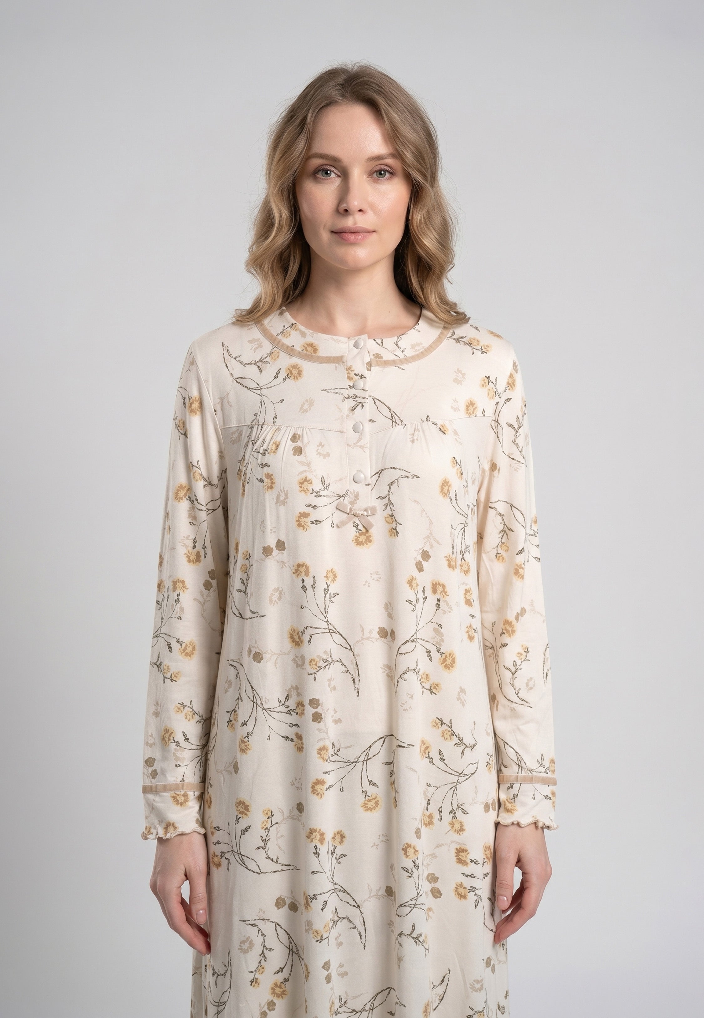 Femme portant une robe de nuit longue col rond boutonné manches longues festonnées imprimé fleuri fleurs sauvages beige et doré sur fond crème Rosabella Soft Bloom