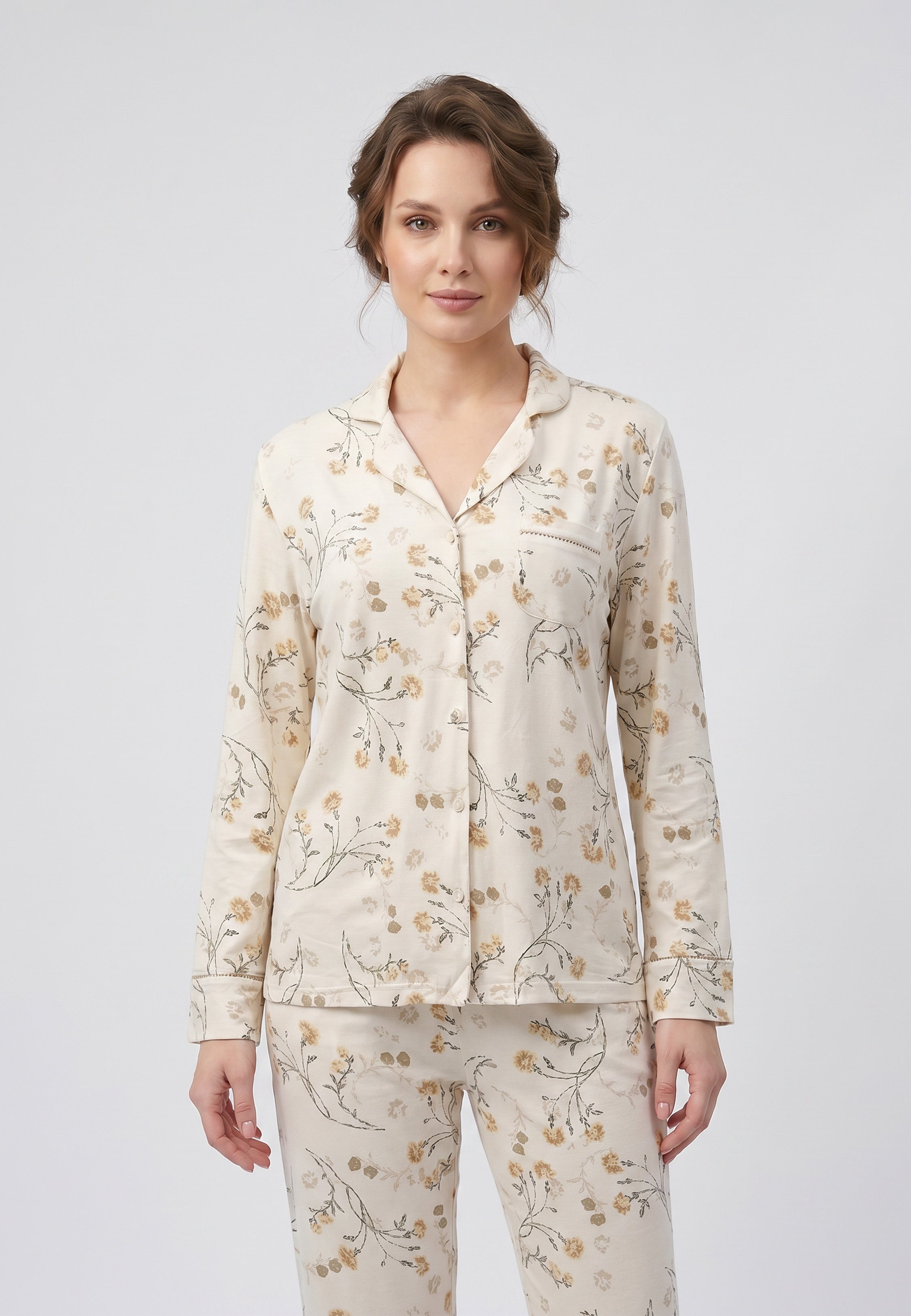 Femme portant un pyjama deux pièces chemise boutonnée col pyjama à revers manches longues poche poitrine imprimé fleuri fleurs sauvages beige et doré sur fond crème et pantalon droit assorti Rosabella Soft Bloom