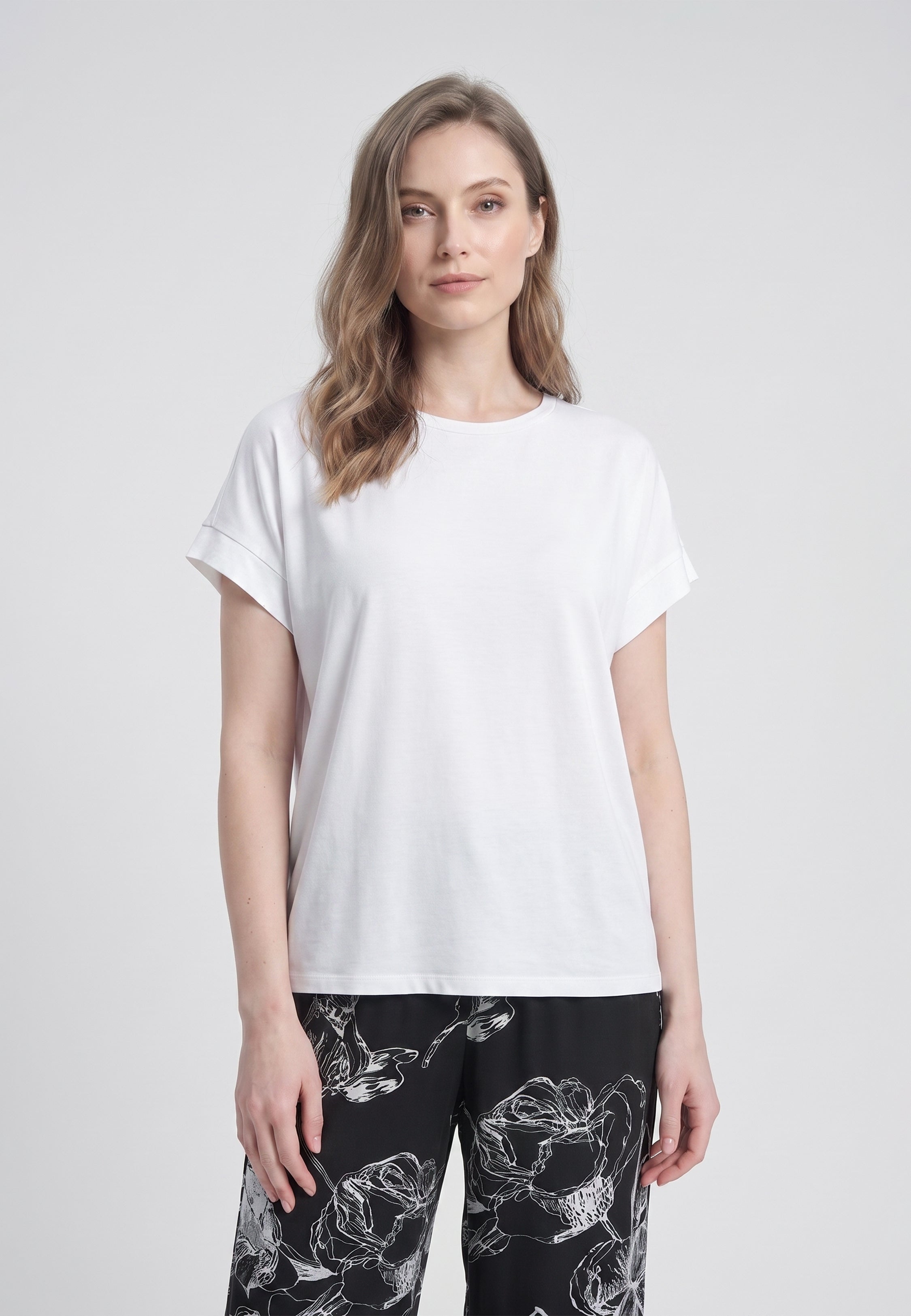 Femme portant un t-shirt écru & pantalon large grandes fleurs écru fond noir Rosabella