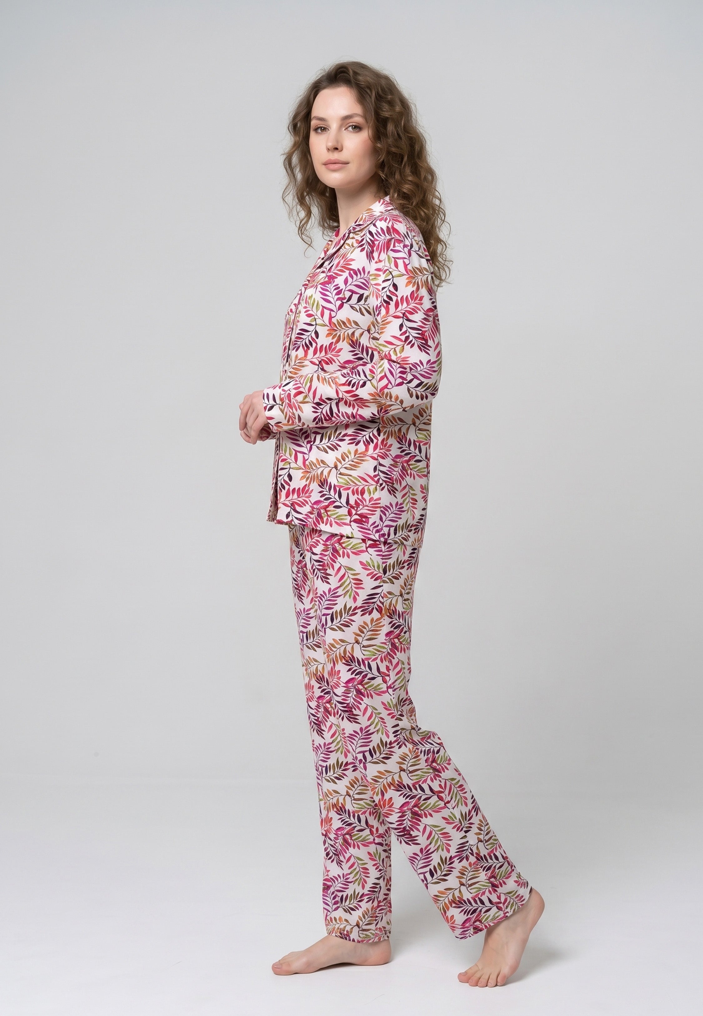 Femme portant un pyjama deux pièces chemise boutonnée col pyjama manches longues imprimé feuillage multicolore rose rouge et doré et pantalon droit assorti Rosabella Soft Bloom