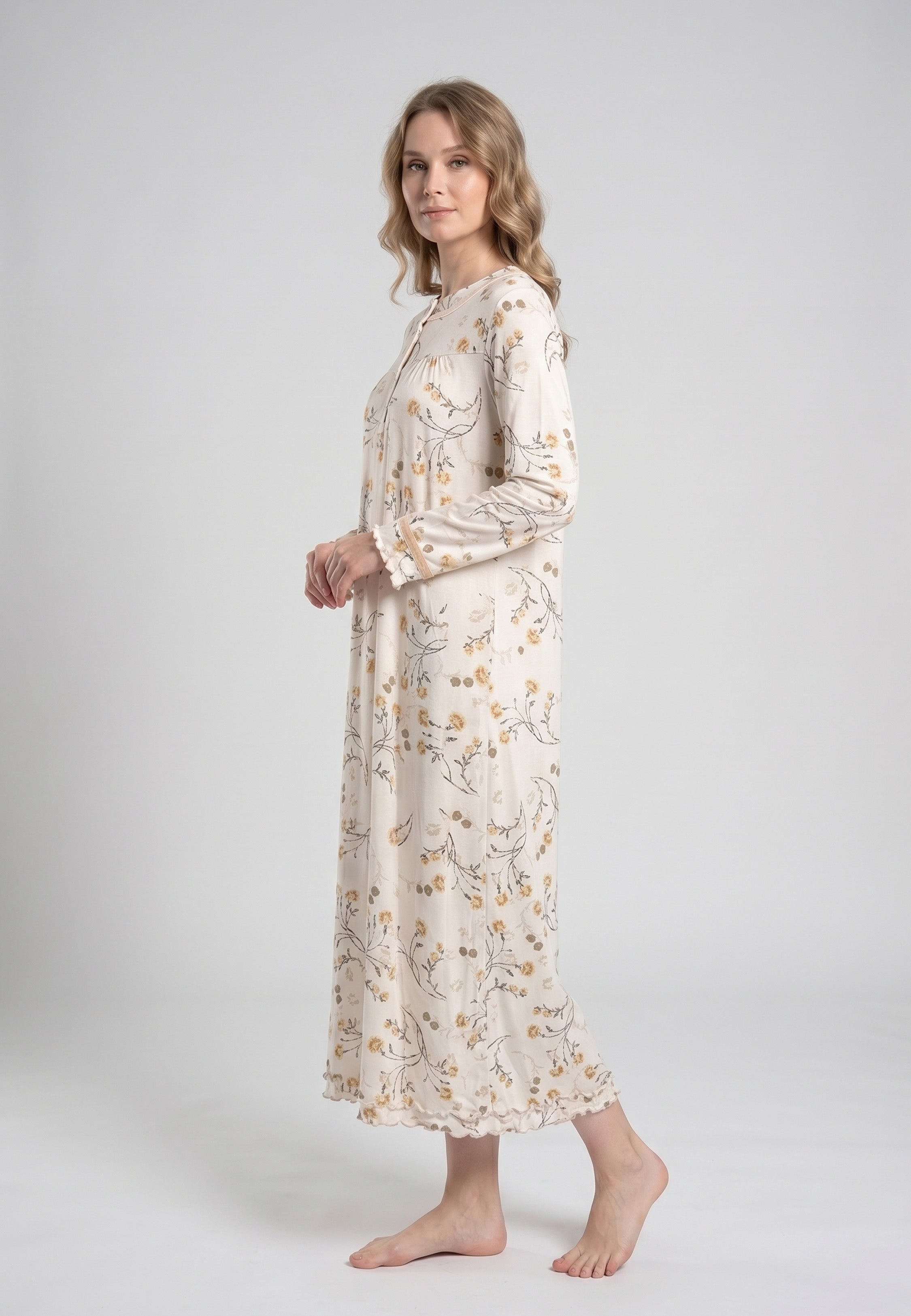 Femme portant une robe de nuit longue col rond boutonné manches longues festonnées imprimé fleuri fleurs sauvages beige et doré sur fond crème Rosabella Soft Bloom