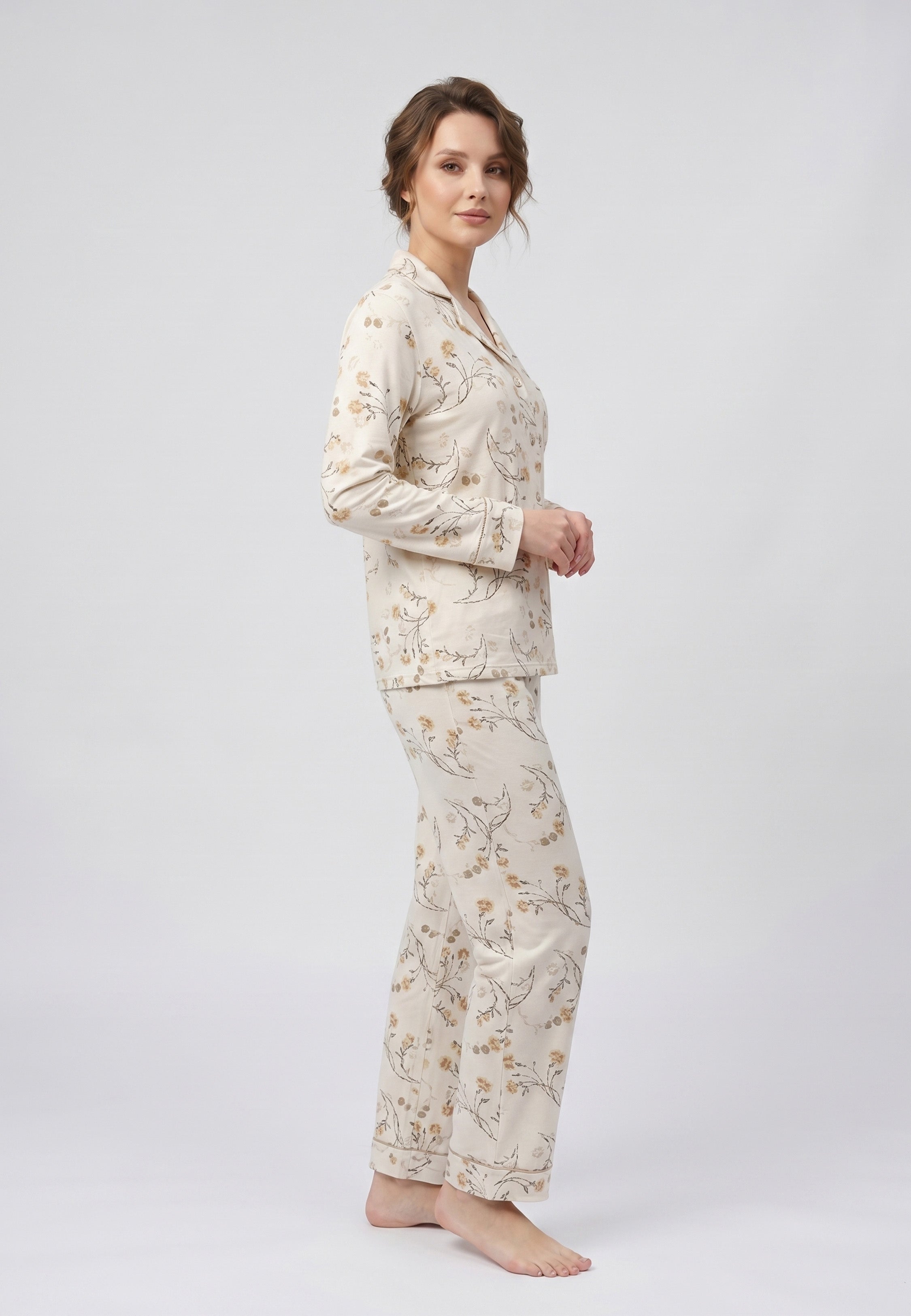 Femme portant un pyjama deux pièces chemise boutonnée col pyjama à revers manches longues poche poitrine imprimé fleuri fleurs sauvages beige et doré sur fond crème et pantalon droit assorti Rosabella Soft Bloom