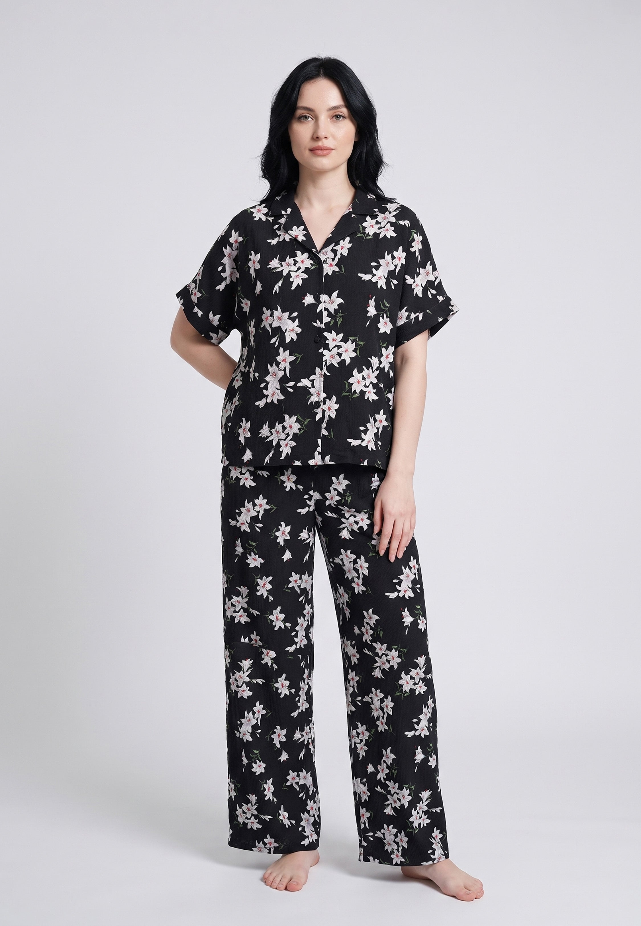 Femme portant un pyjama chemise manches courtes et pantalon large imprimé lys blancs sur fond noir Rosabella