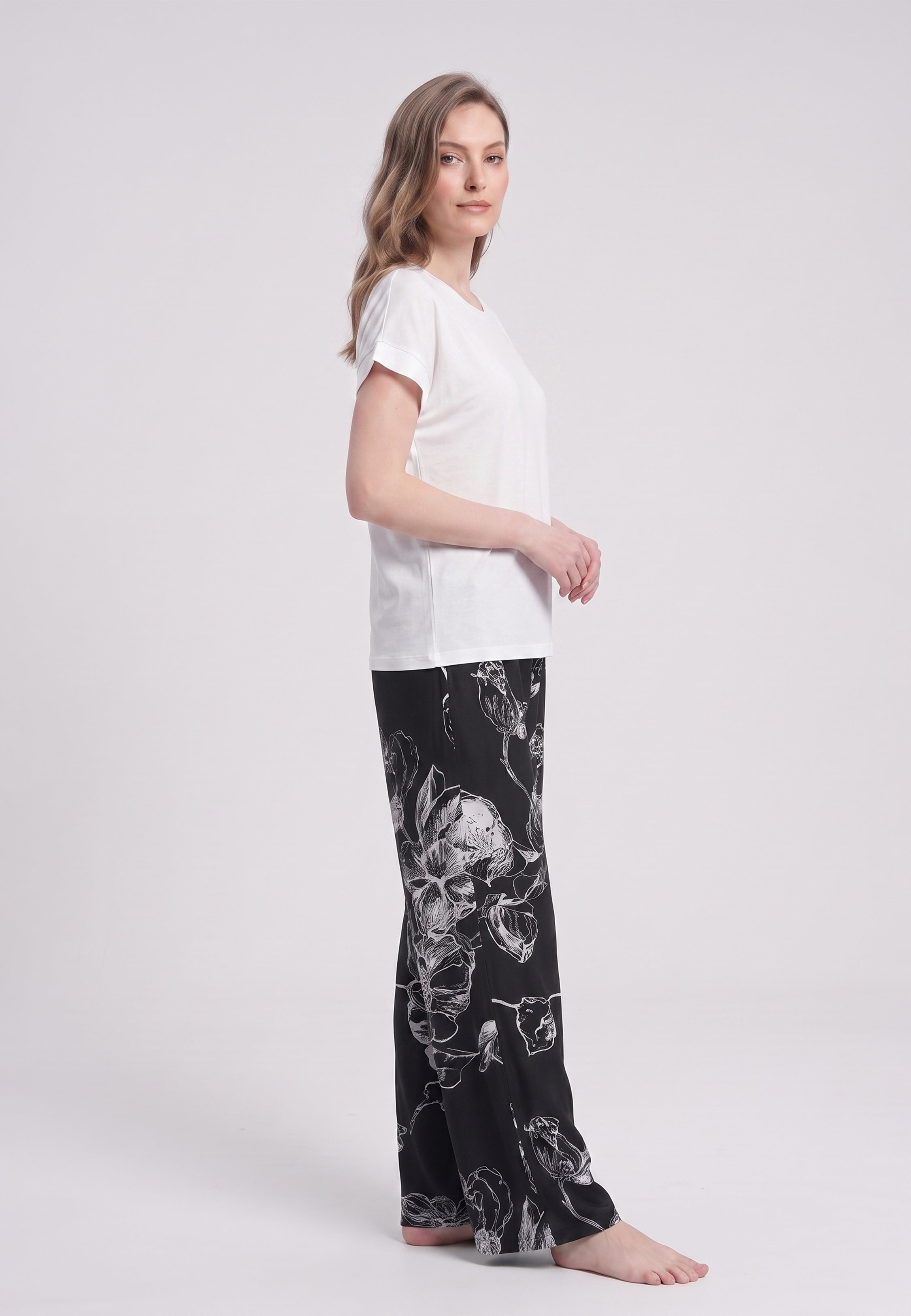 Femme portant un t-shirt écru & pantalon large grandes fleurs écru fond noir Rosabella