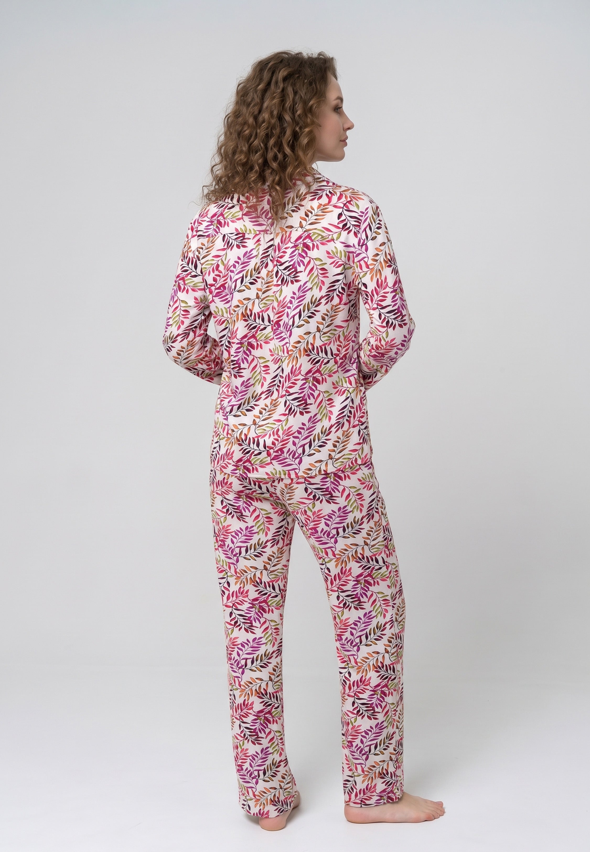 Femme portant un pyjama deux pièces chemise boutonnée col pyjama manches longues imprimé feuillage multicolore rose rouge et doré et pantalon droit assorti Rosabella Soft Bloom