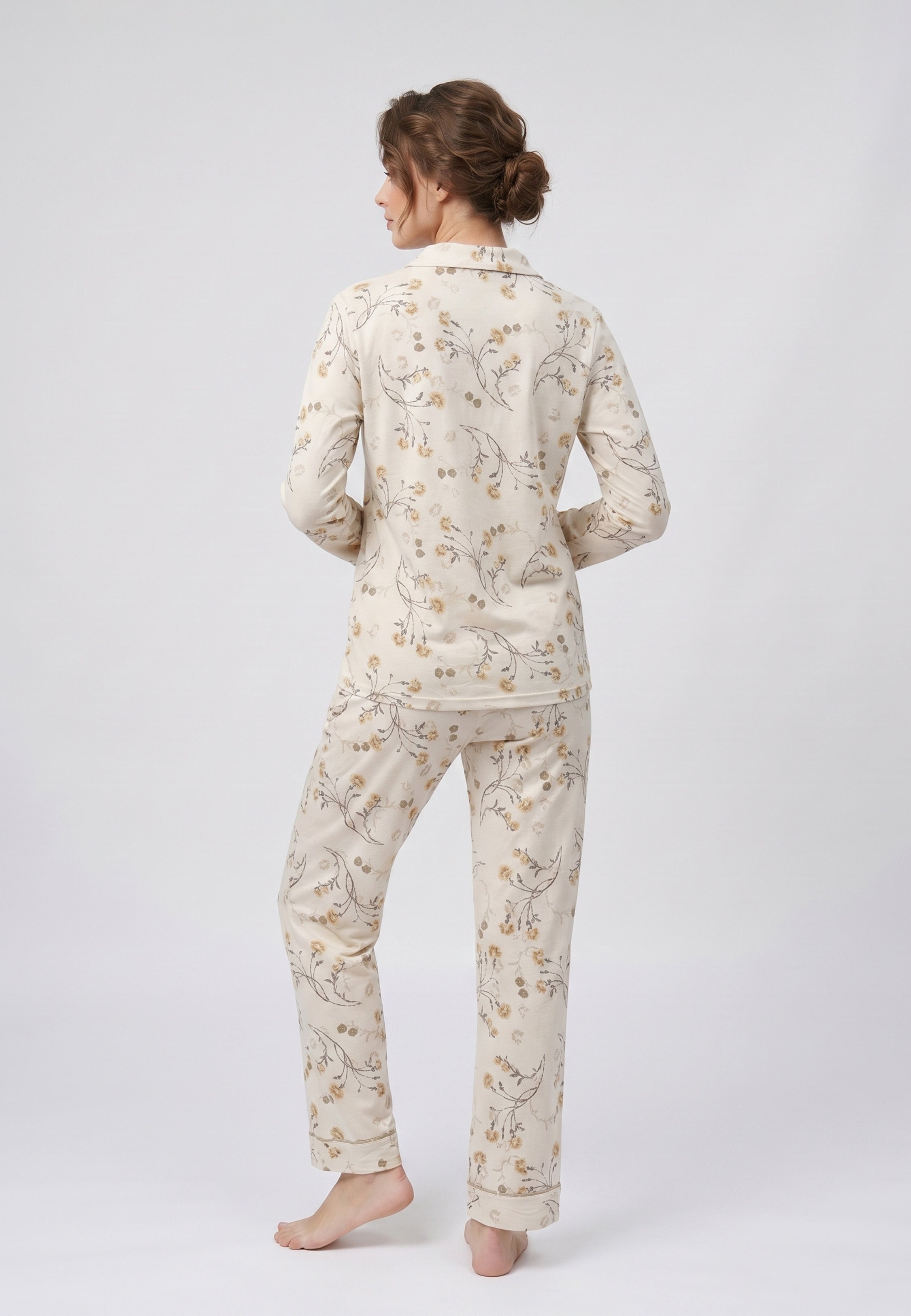 Femme portant un pyjama deux pièces chemise boutonnée col pyjama à revers manches longues poche poitrine imprimé fleuri fleurs sauvages beige et doré sur fond crème et pantalon droit assorti Rosabella Soft Bloom