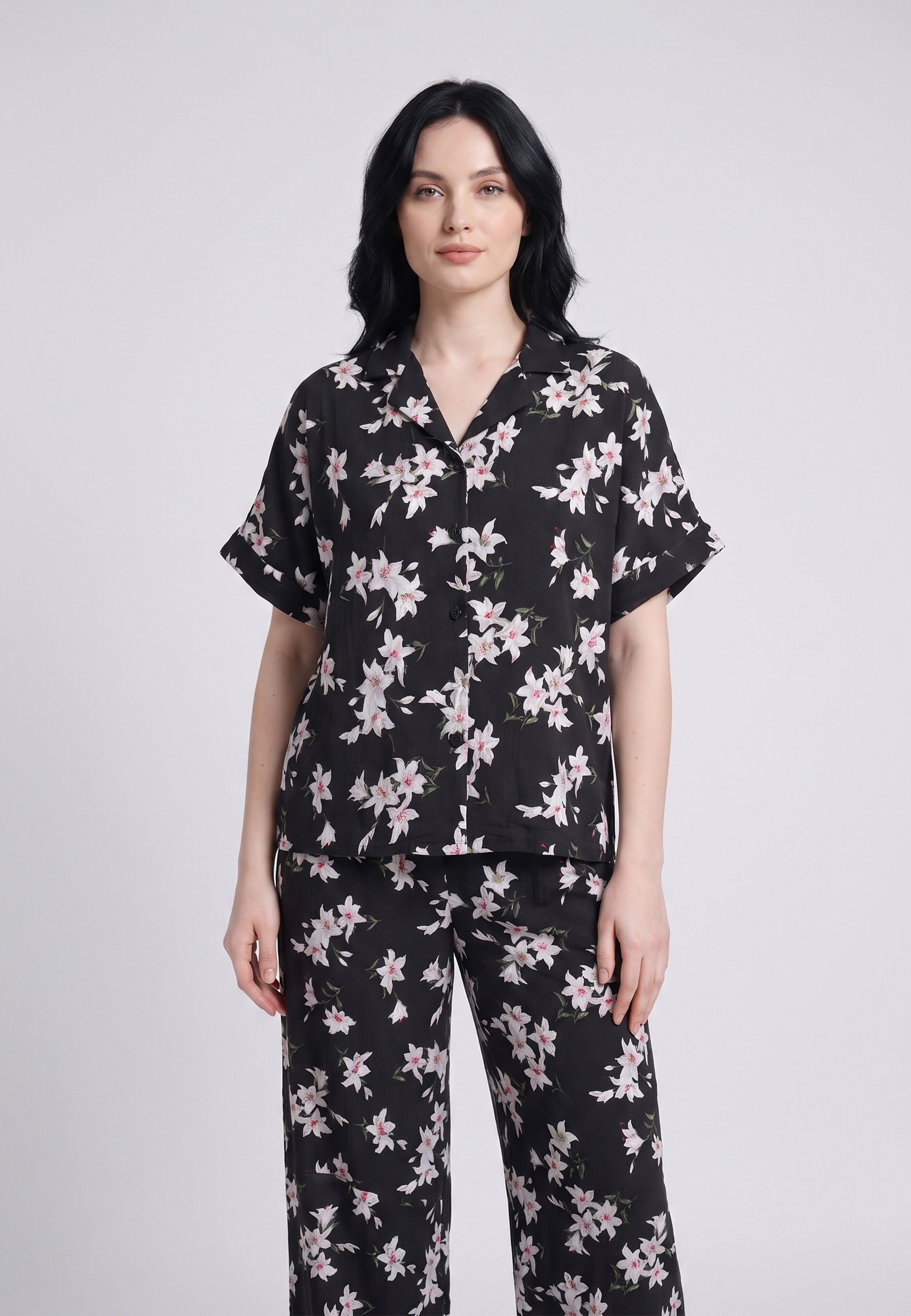 Femme portant un pyjama chemise manches courtes et pantalon large imprimé lys blancs sur fond noir Rosabella