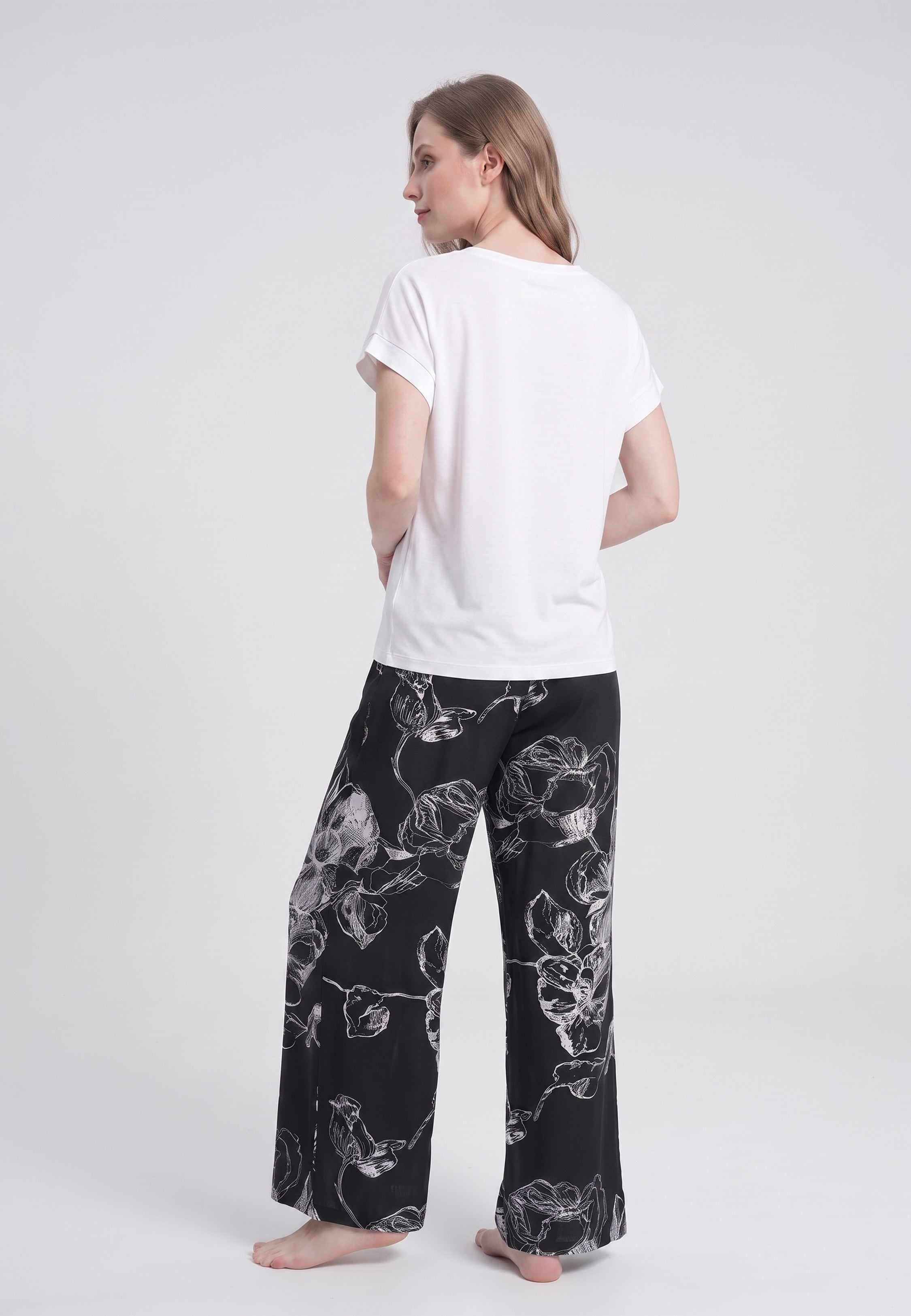 Femme portant un t-shirt écru & pantalon large grandes fleurs écru fond noir Rosabella