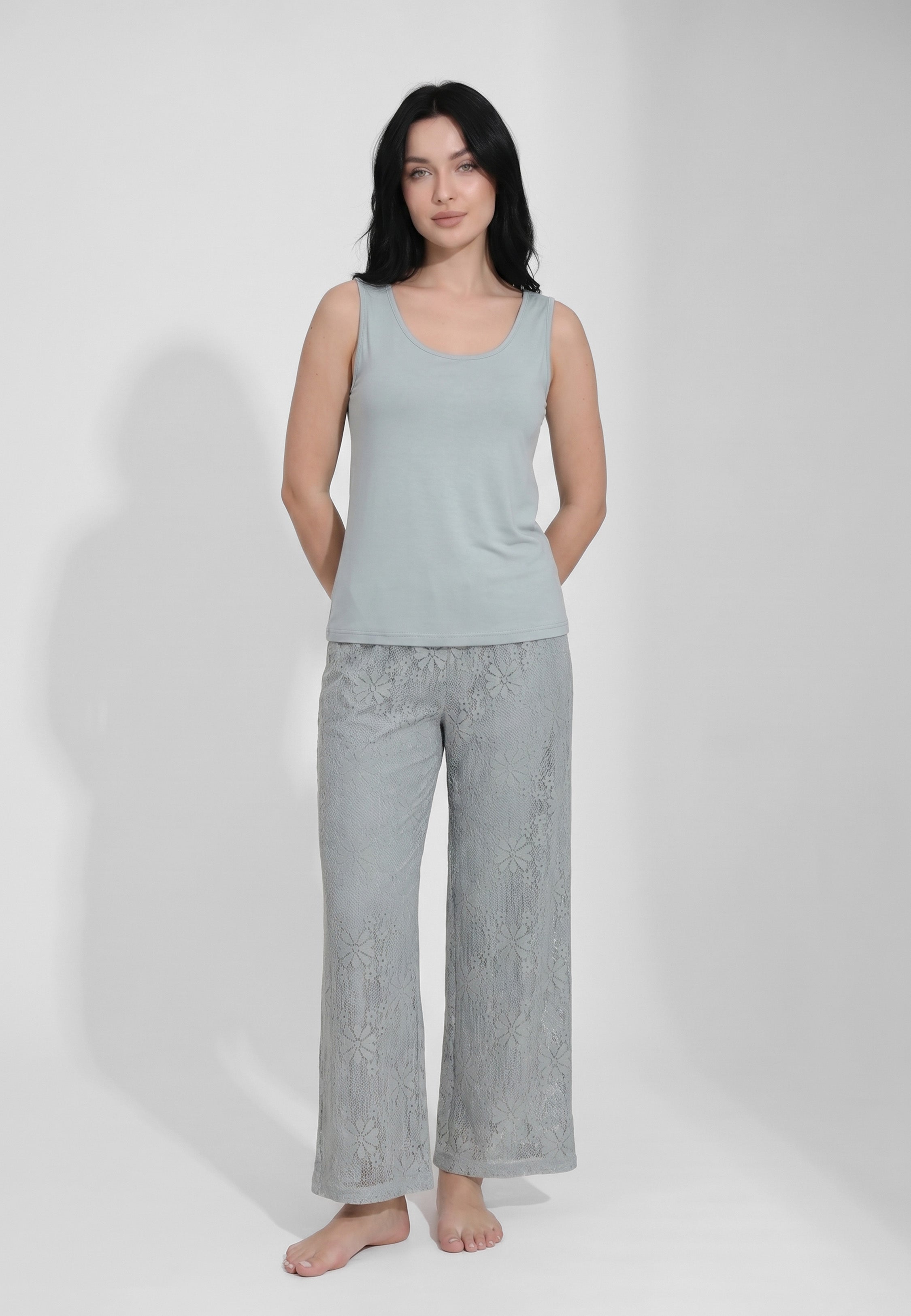 Femme portant un ensemble débardeur col rond bretelles larges bleu acier et pantalon large dentelle florale transparente motif marguerites Rosabella