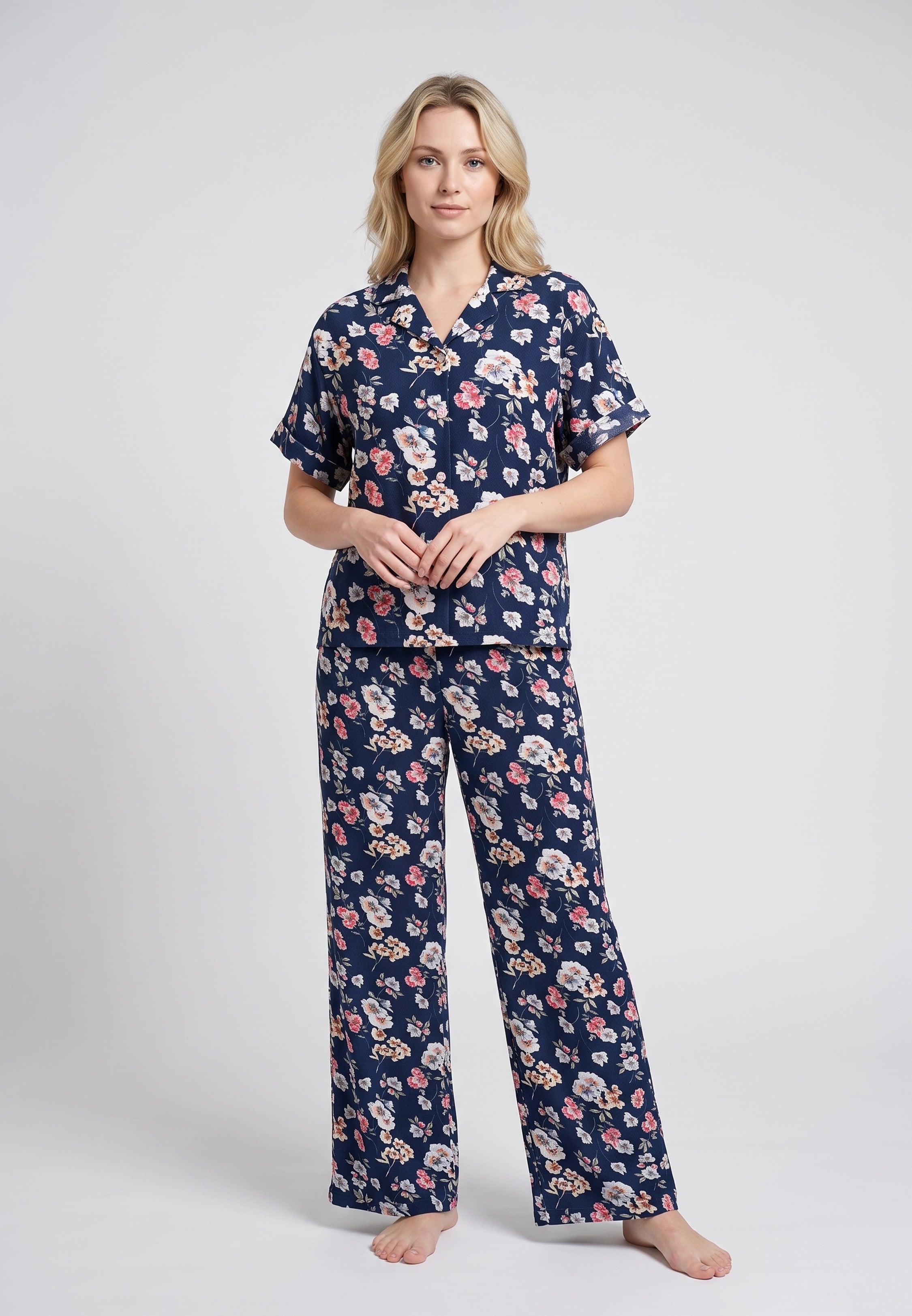 Femme portant un pyjama chemise manches courtes et pantalon large imprimé fleuri rose sur fond marine Rosabella