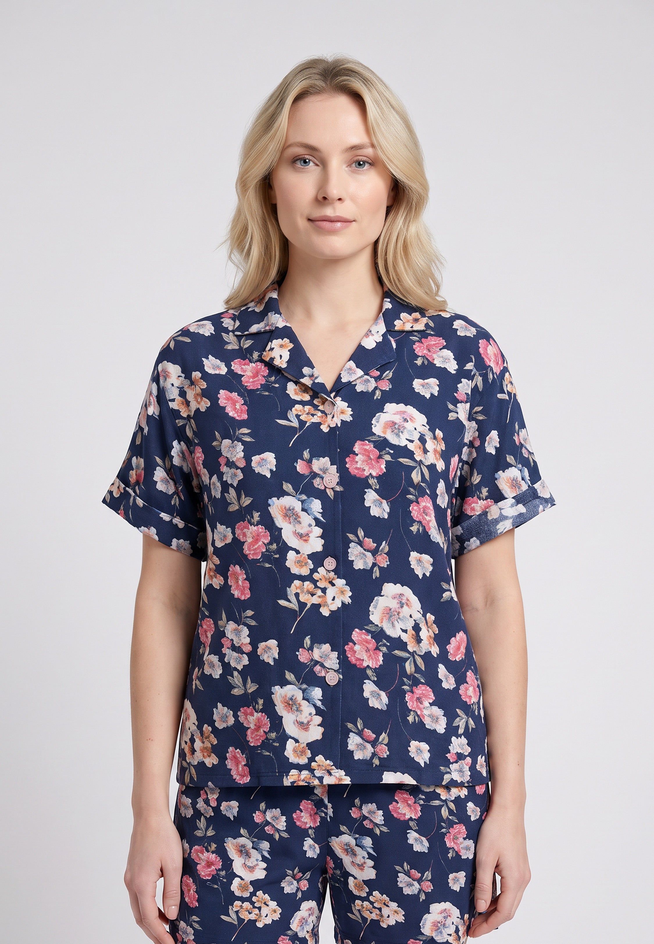 Femme portant un pyjama chemise manches courtes et pantalon large imprimé fleuri rose sur fond marine Rosabella