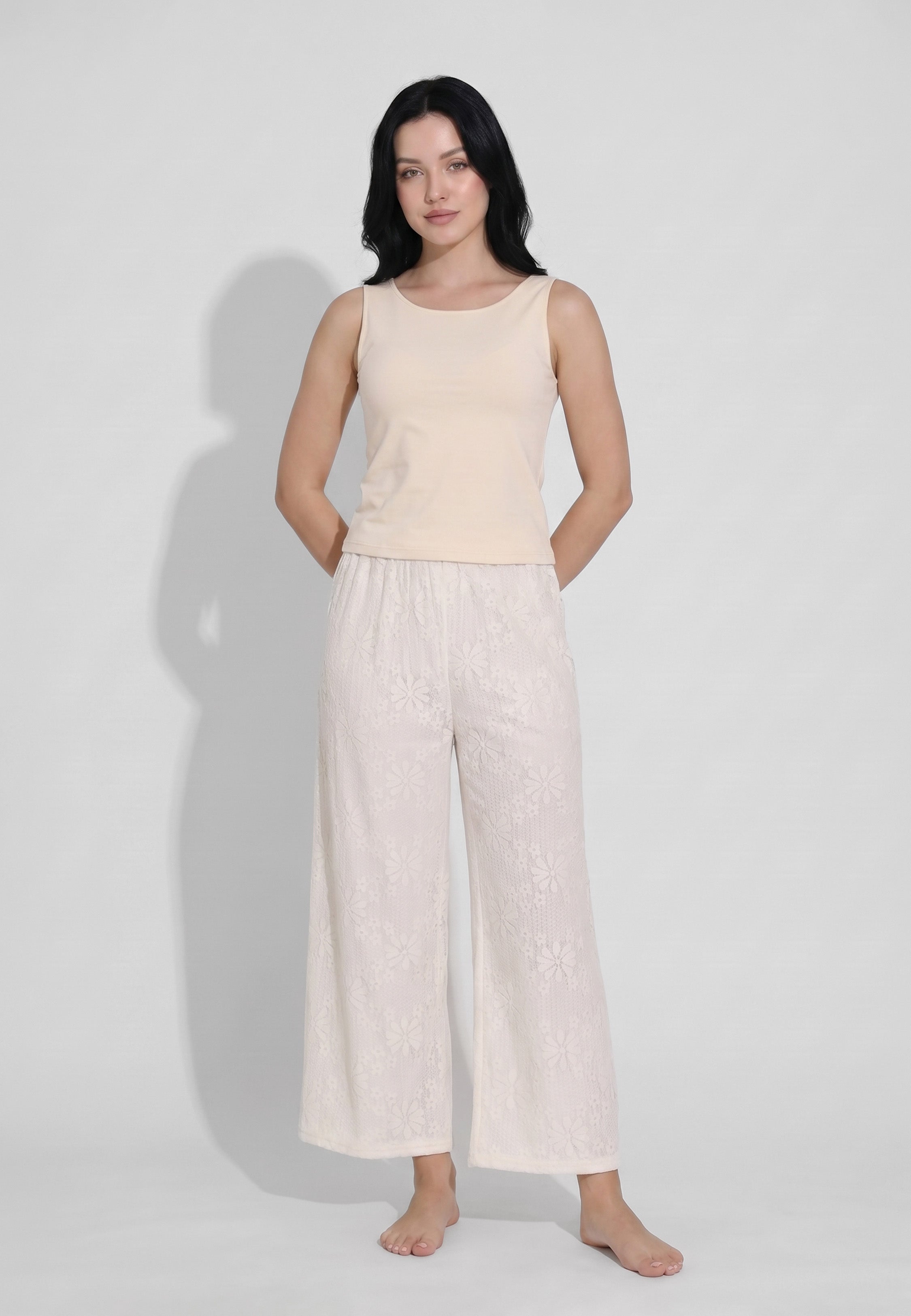 Femme portant un ensemble débardeur col rond bretelles larges sable et pantalon large dentelle florale ivoire transparente motif marguerites Rosabella