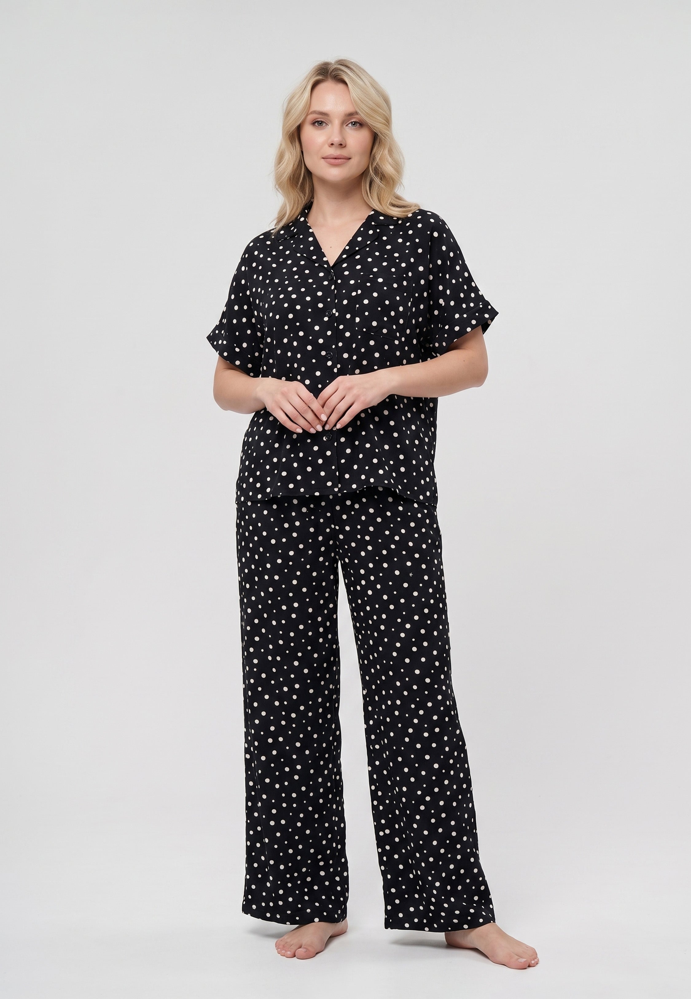 Femme portant un pyjama chemise manches courtes et pantalon large imprimé pois crème sur fond noir Rosabella