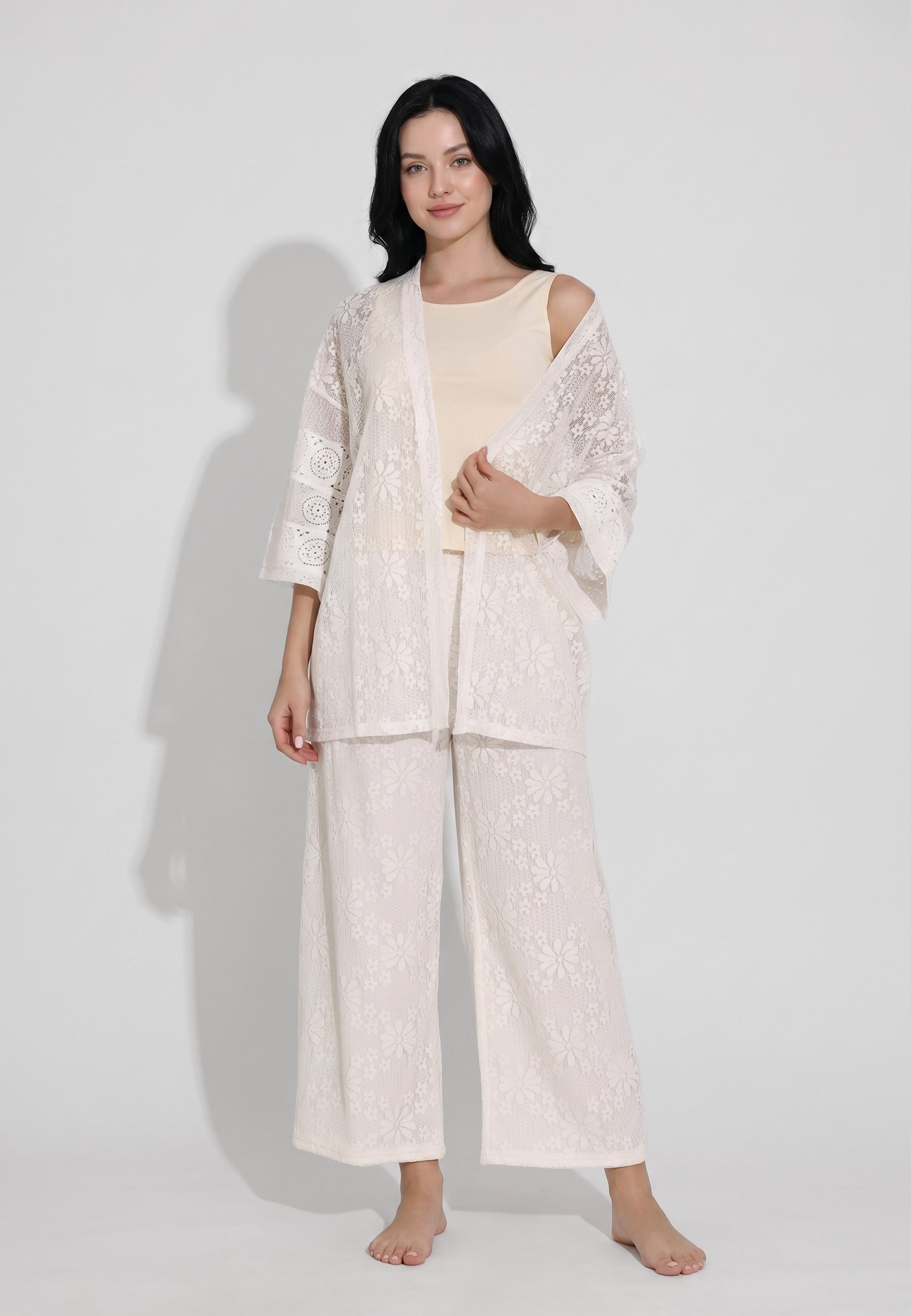 Femme portant un ensemble débardeur col rond bretelles larges sable et pantalon large dentelle florale ivoire transparente motif marguerites Rosabella