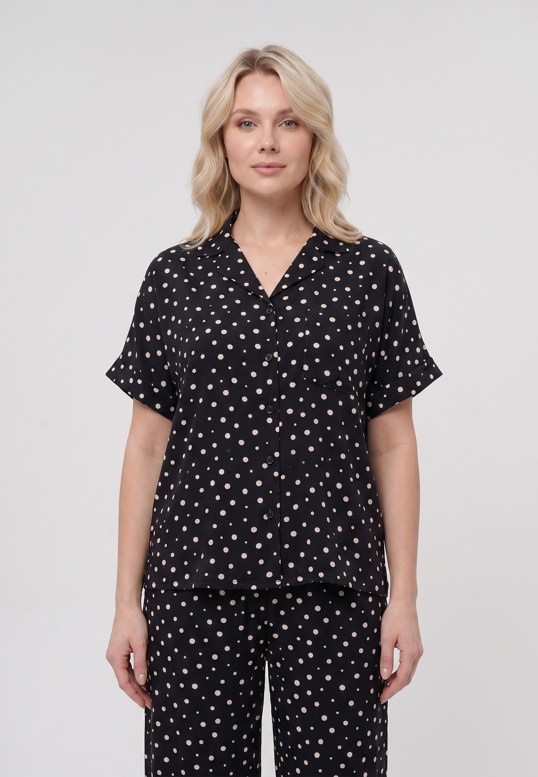 Femme portant un pyjama chemise manches courtes et pantalon large imprimé pois crème sur fond noir Rosabella