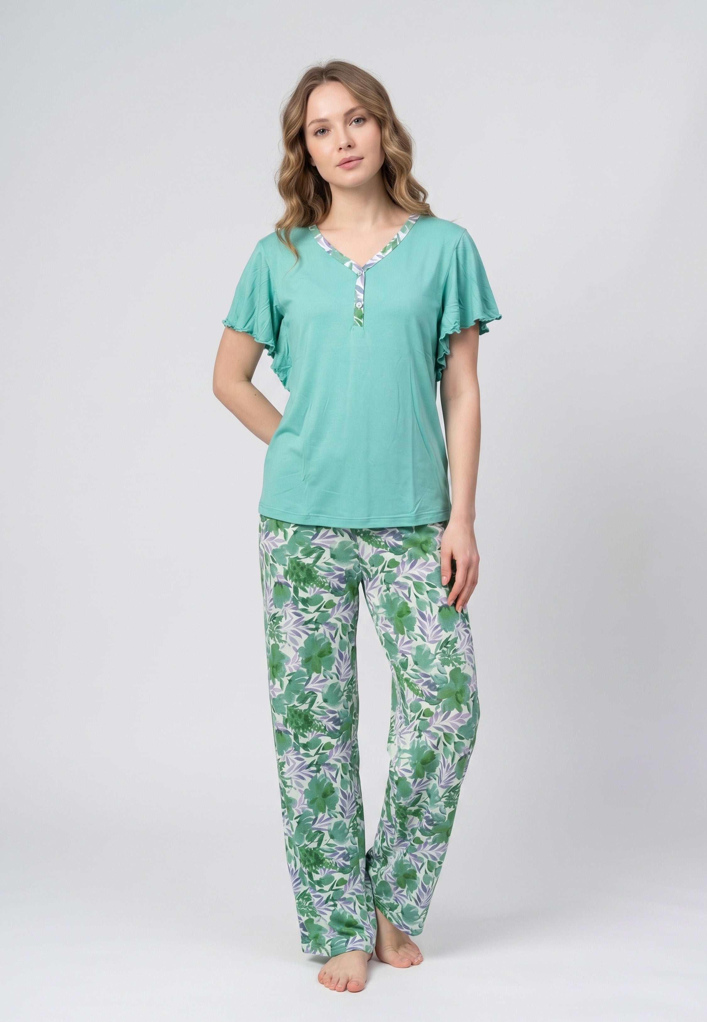 Femme portant un pyjama deux pièces haut turquoise manches papillon et pantalon à imprimé floral vert et violet