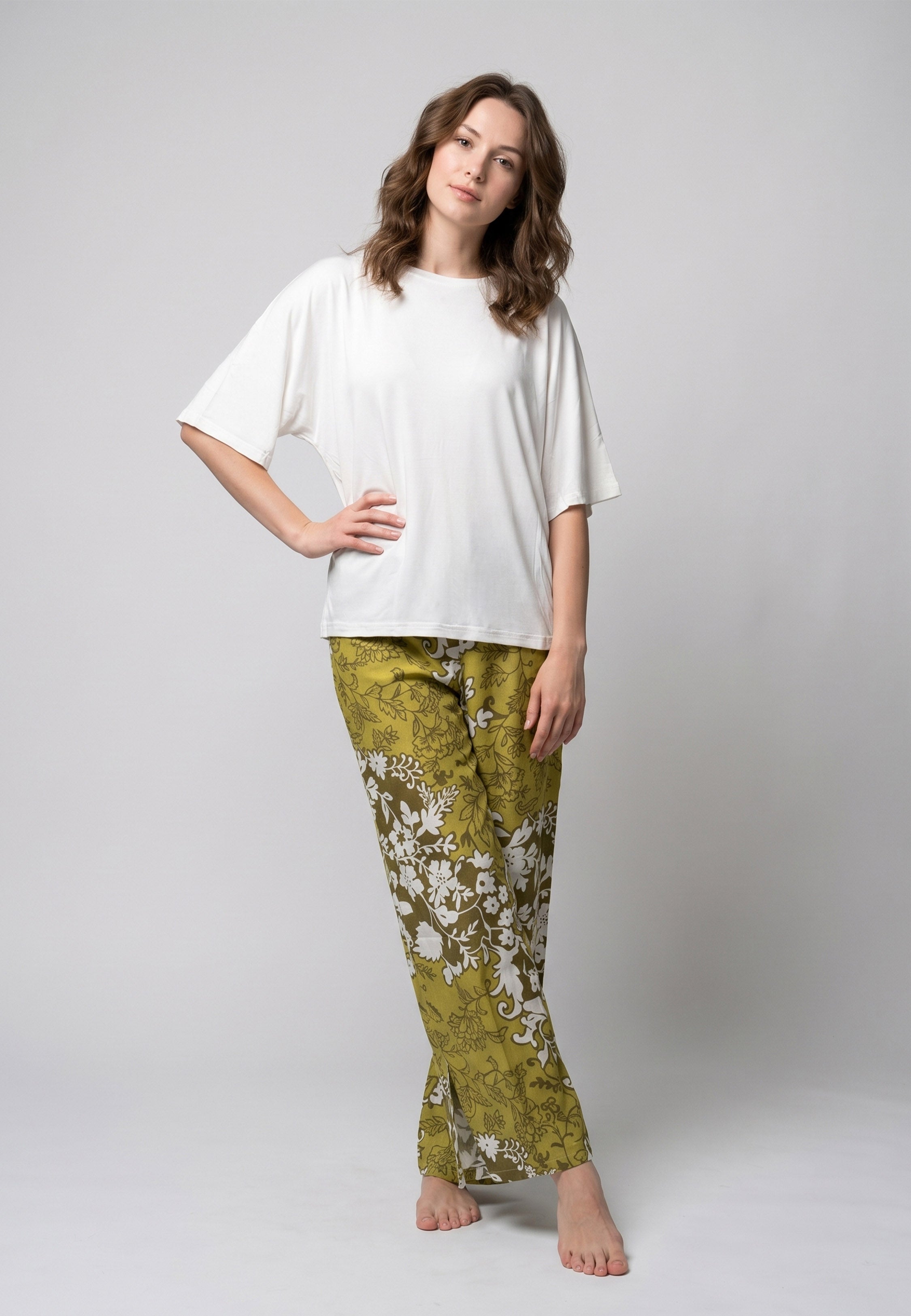 Femme portant un pyjama deux pièces t-shirt oversize uni blanc et pantalon large imprimé fleuri blanc sur fond vert kaki Rosabella Cozy Comforts