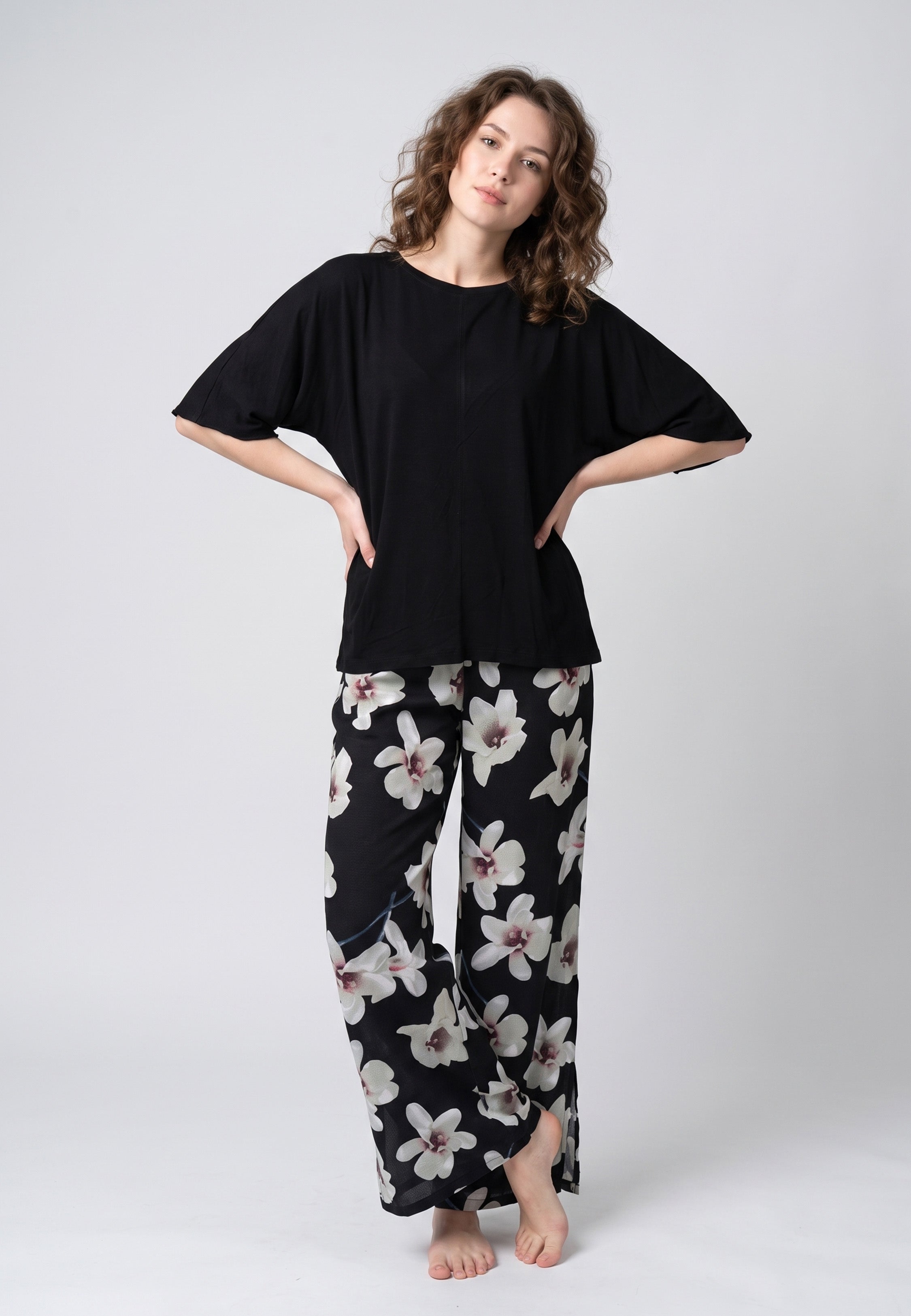 Pyjama pantalon long deux pièces T-shirt col rond noir manches papillon évasées et pantalon large fond noir imprimé grandes orchidées blanc et gris
