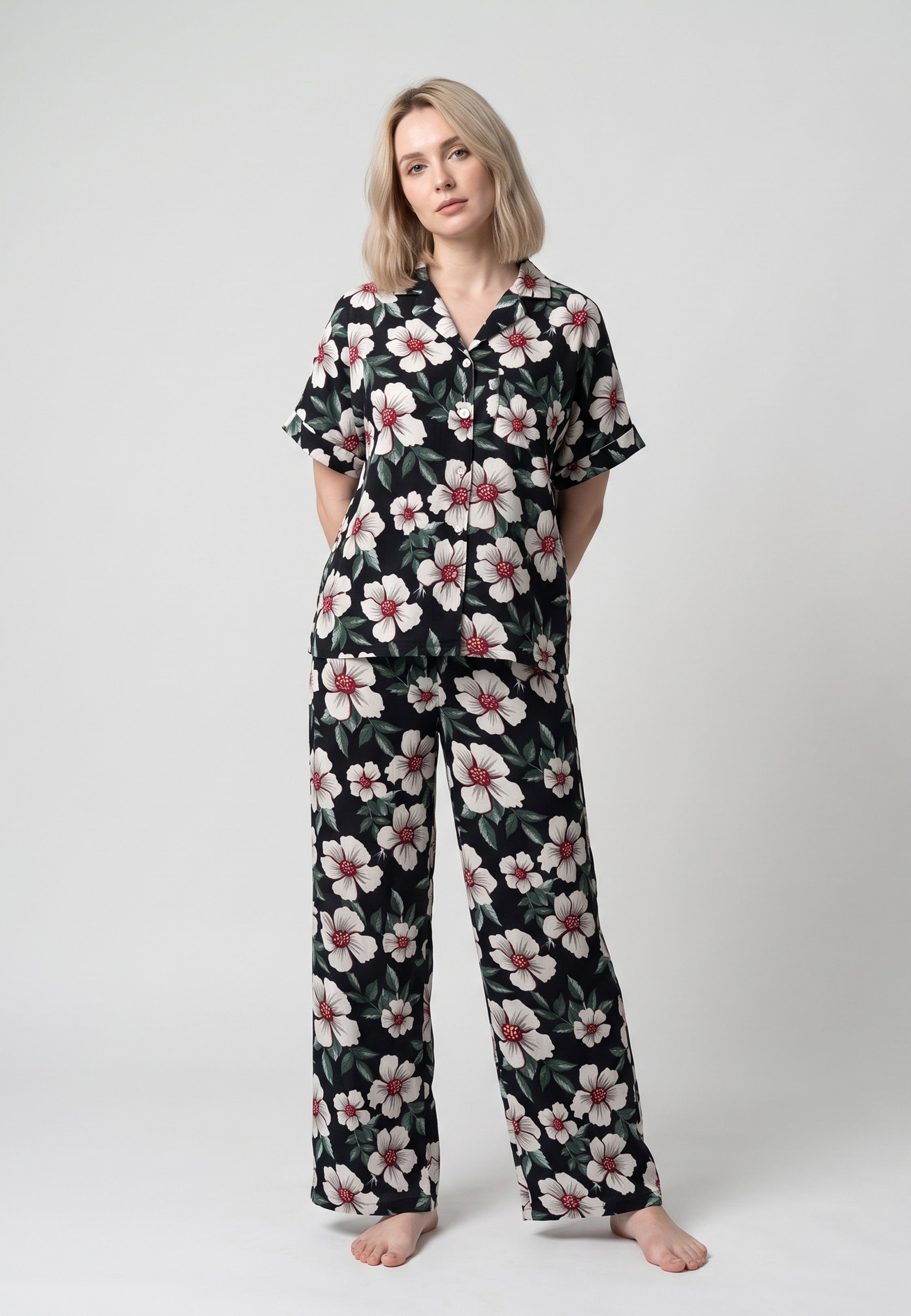 Femme portant un pyjama chemise manches courtes et pantalon large grandes fleurs écrues cœur bordeaux sur fond noir Rosabella