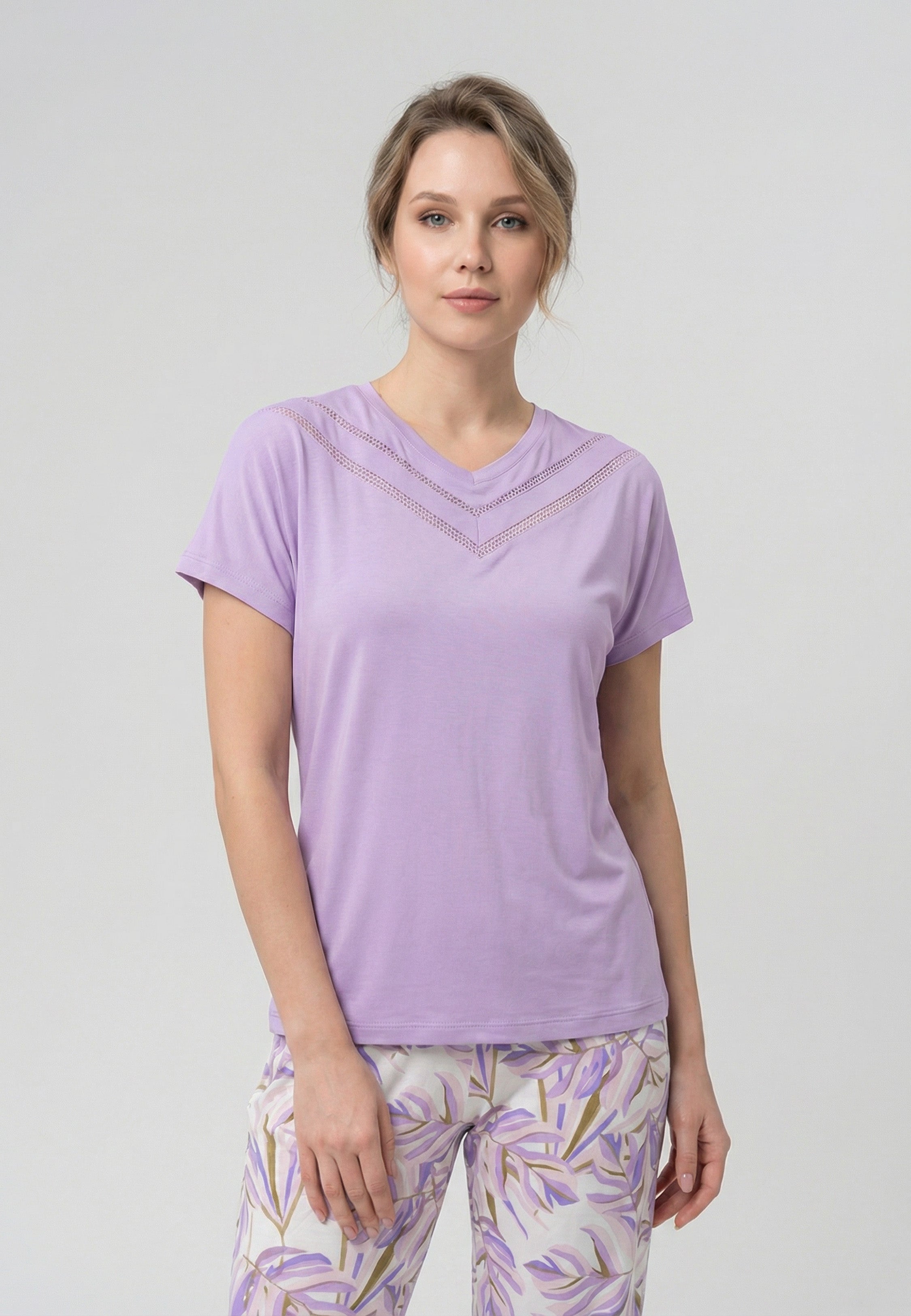 Femme portant un pyjama deux pièces t-shirt mauve clair col V dentelle et pantalon long imprimé feuillage botanique mauve et doré Rosabella Fleurs Sauvages