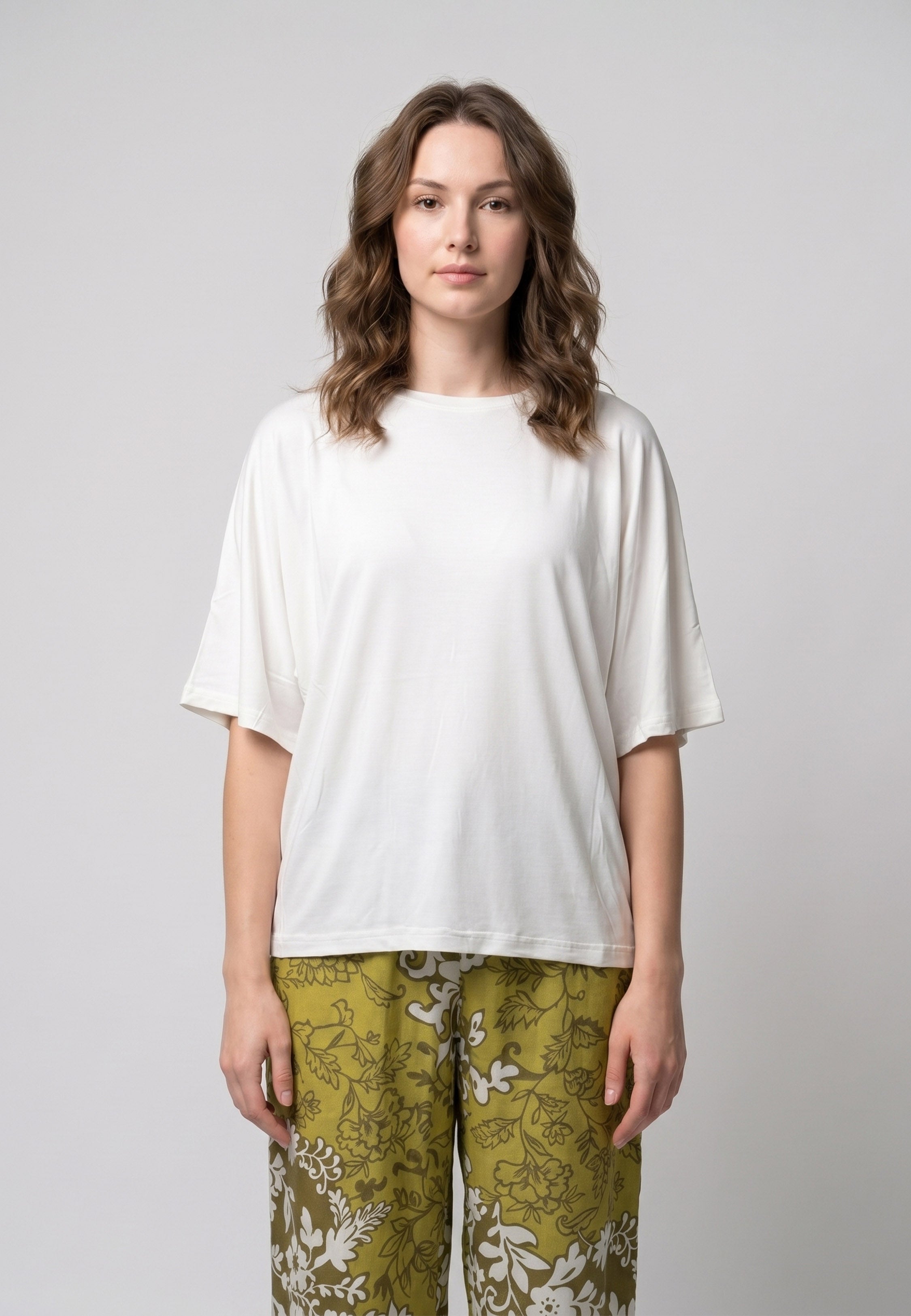 Femme portant un pyjama deux pièces t-shirt oversize uni blanc et pantalon large imprimé fleuri blanc sur fond vert kaki Rosabella Cozy Comforts