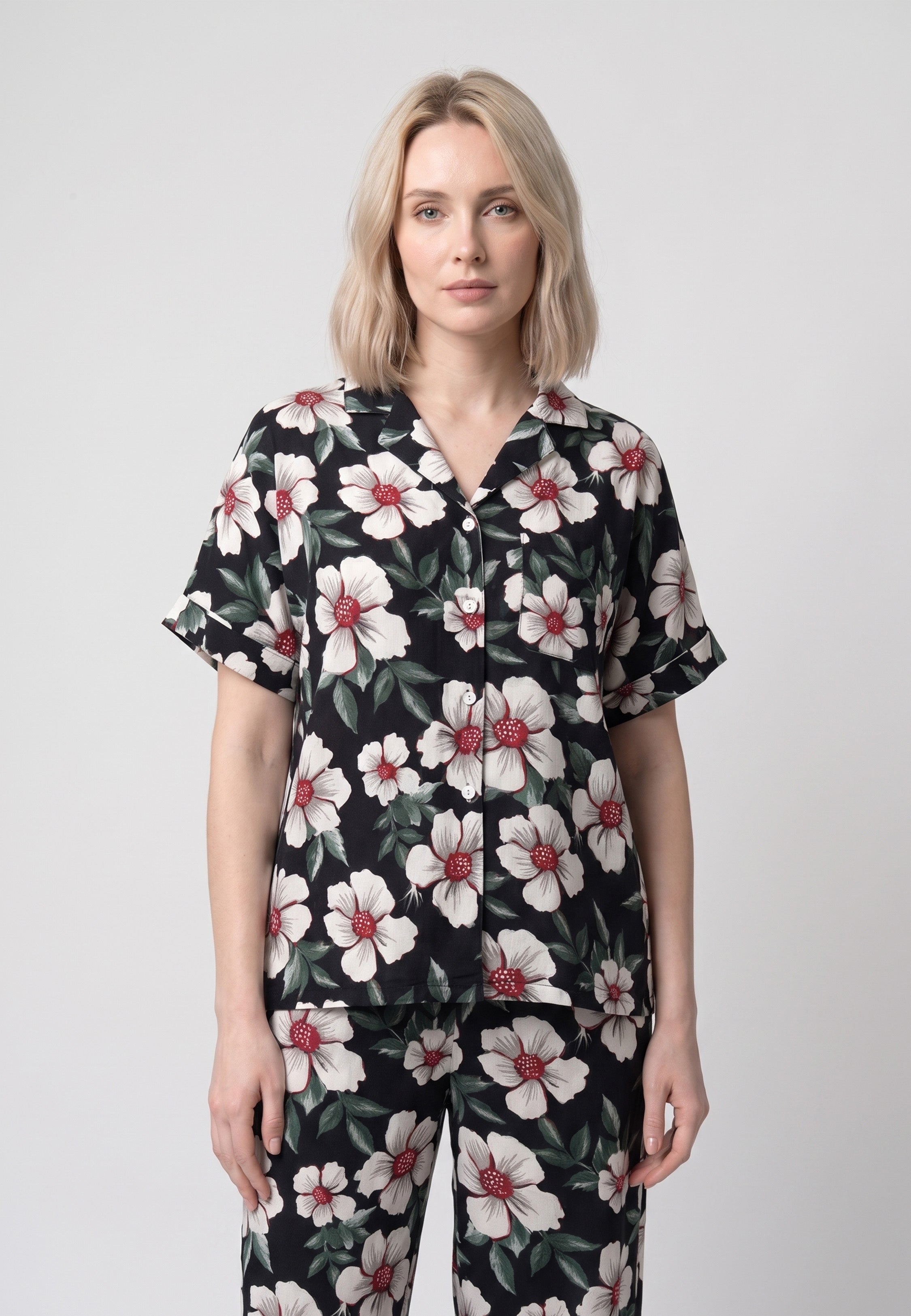 Femme portant un pyjama chemise manches courtes et pantalon large grandes fleurs écrues cœur bordeaux sur fond noir Rosabella