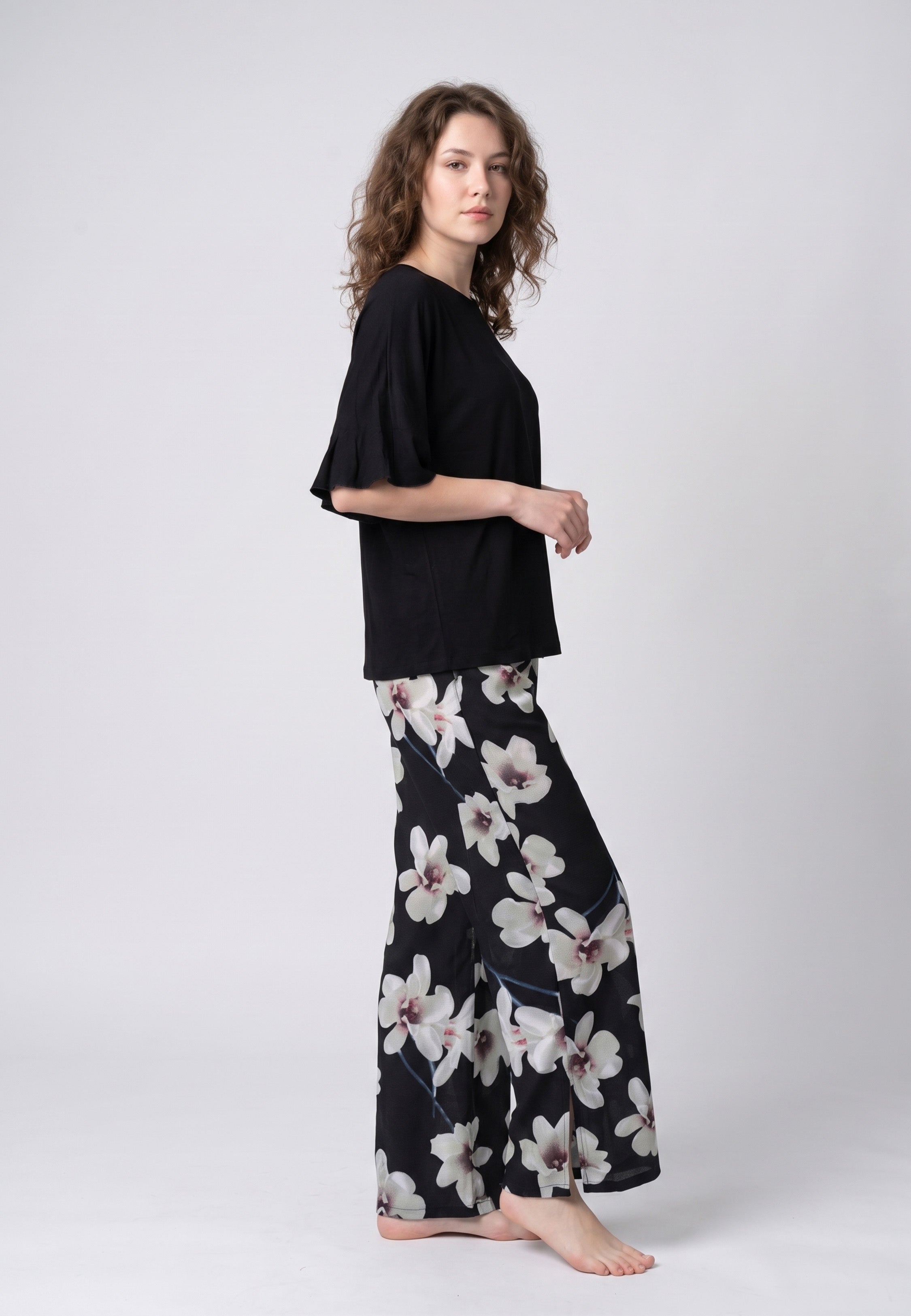 Pyjama pantalon long deux pièces T-shirt col rond noir manches papillon évasées et pantalon large fond noir imprimé grandes orchidées blanc et gris