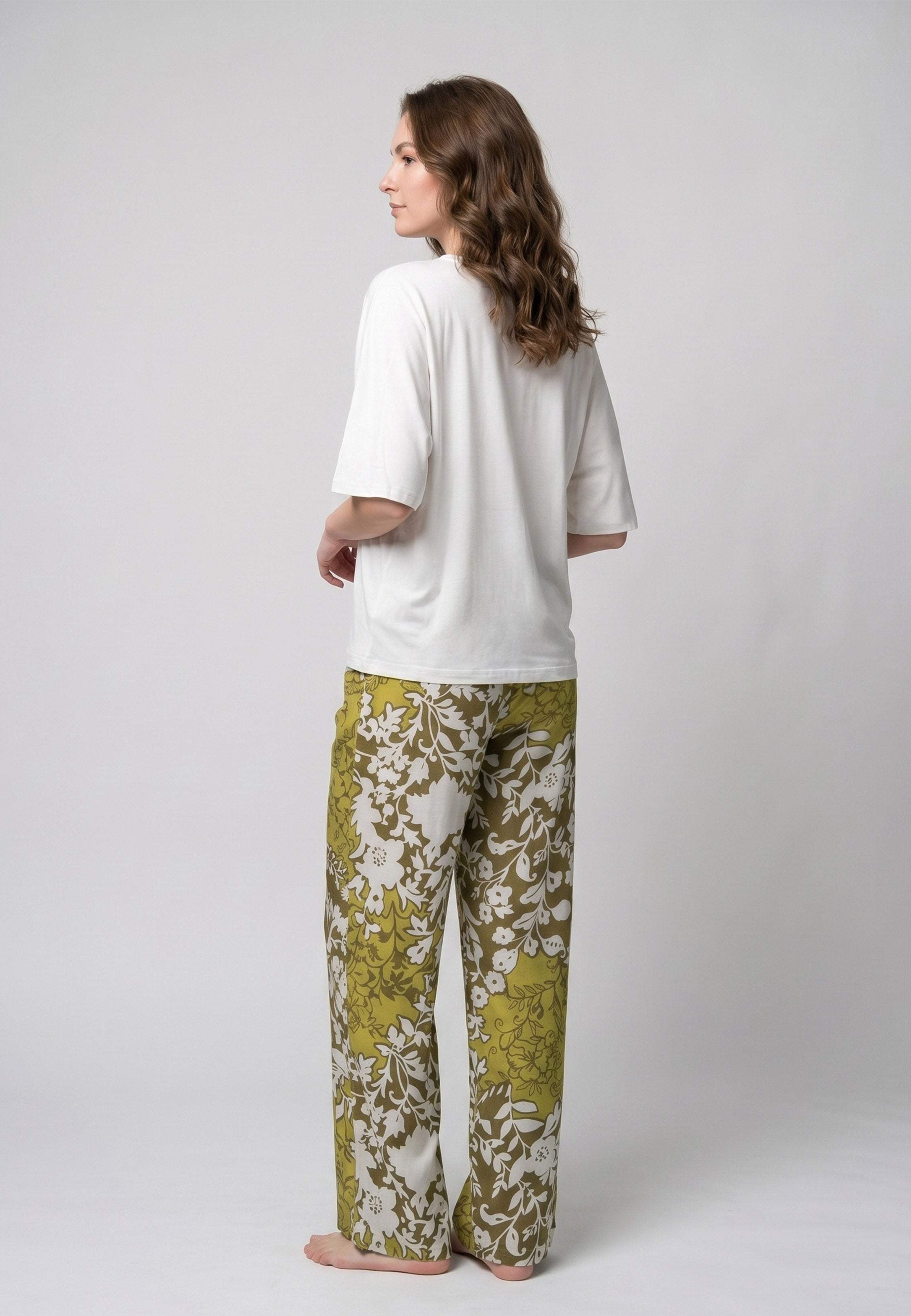 Femme portant un pyjama deux pièces t-shirt oversize uni blanc et pantalon large imprimé fleuri blanc sur fond vert kaki Rosabella Cozy Comforts