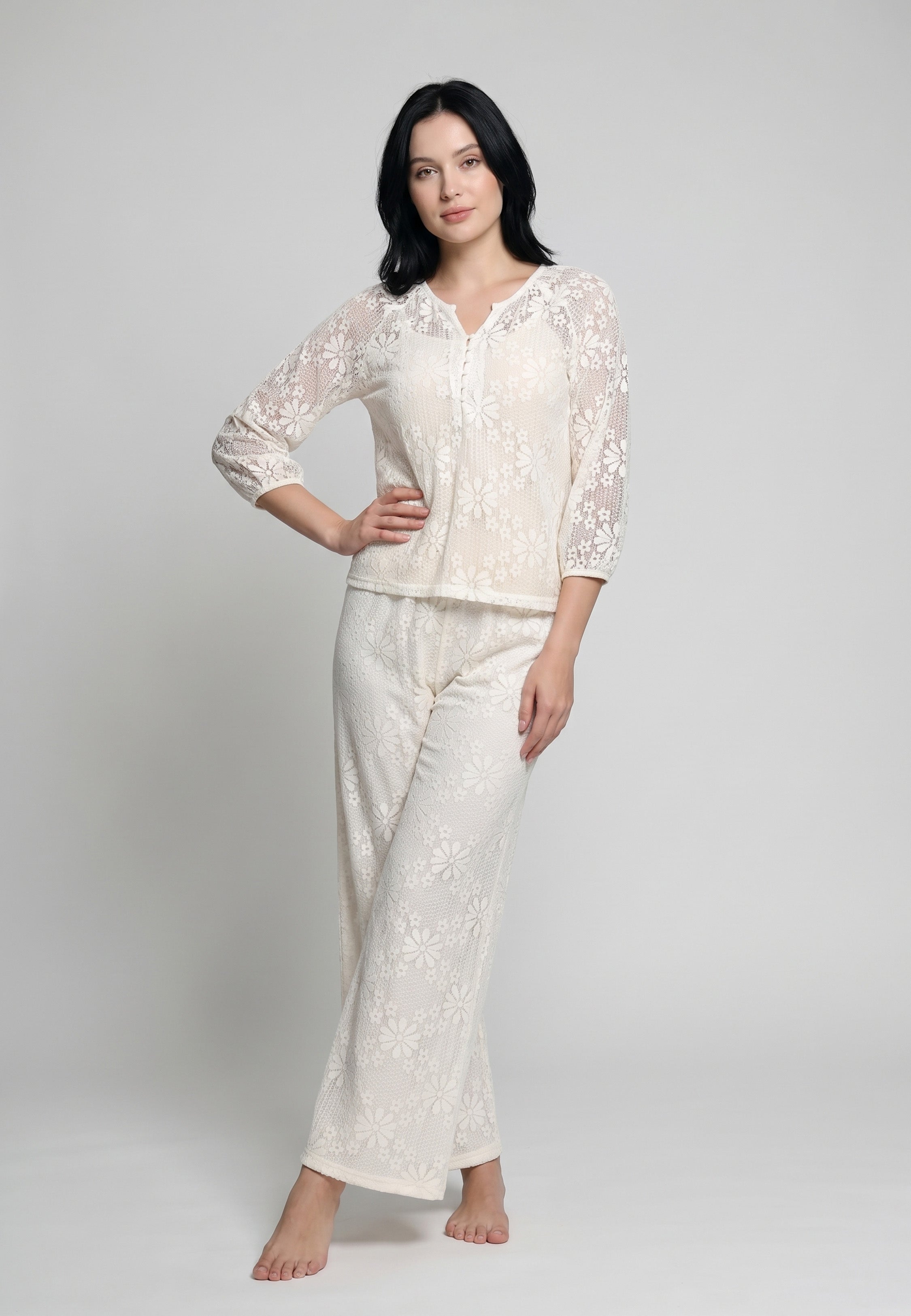 Femme portant un ensemble caraco à bretelles fines sable nude et pantalon large dentelle florale ivoire transparente motif marguerites Rosabella