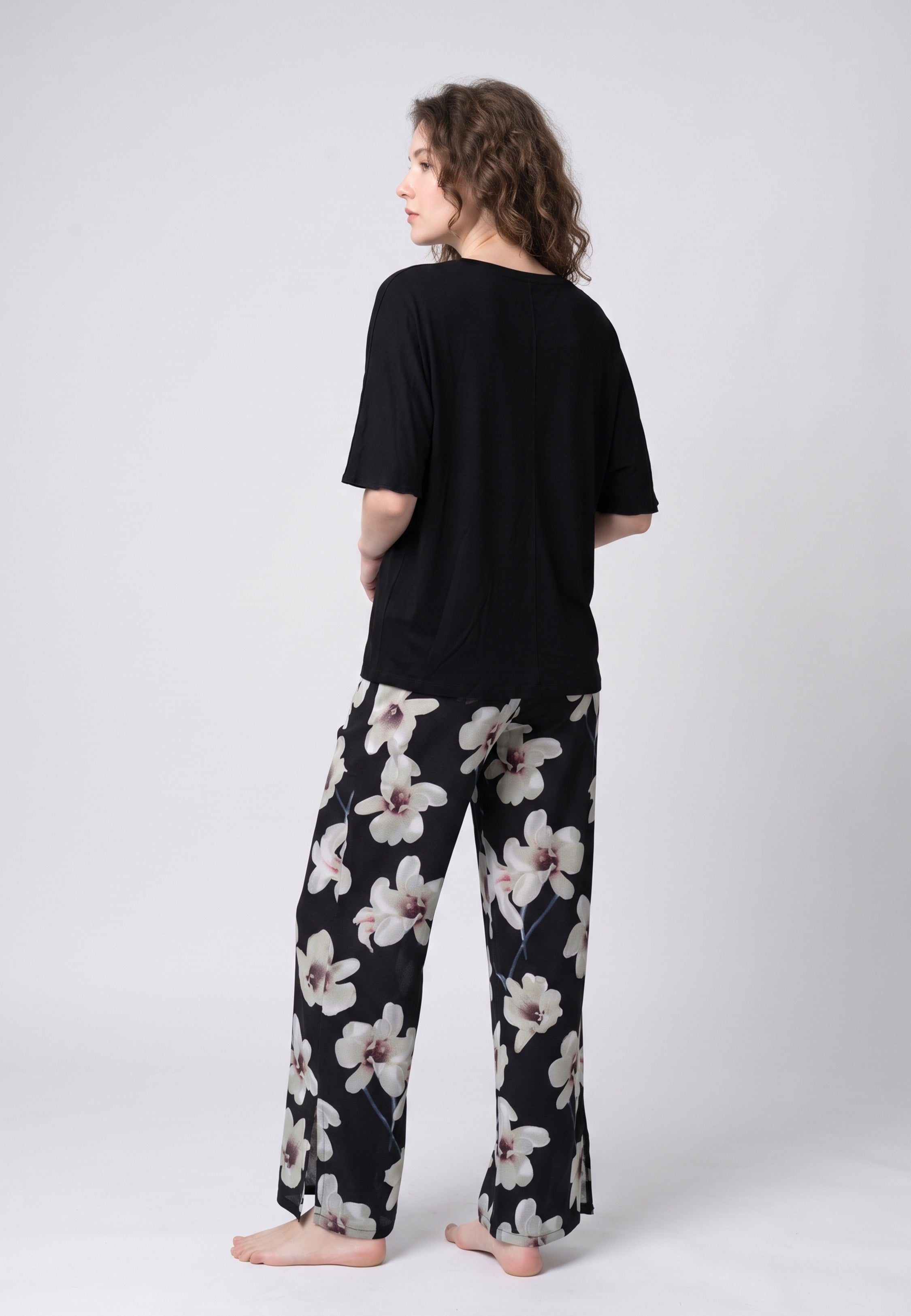 Pyjama pantalon long deux pièces T-shirt col rond noir manches papillon évasées et pantalon large fond noir imprimé grandes orchidées blanc et gris