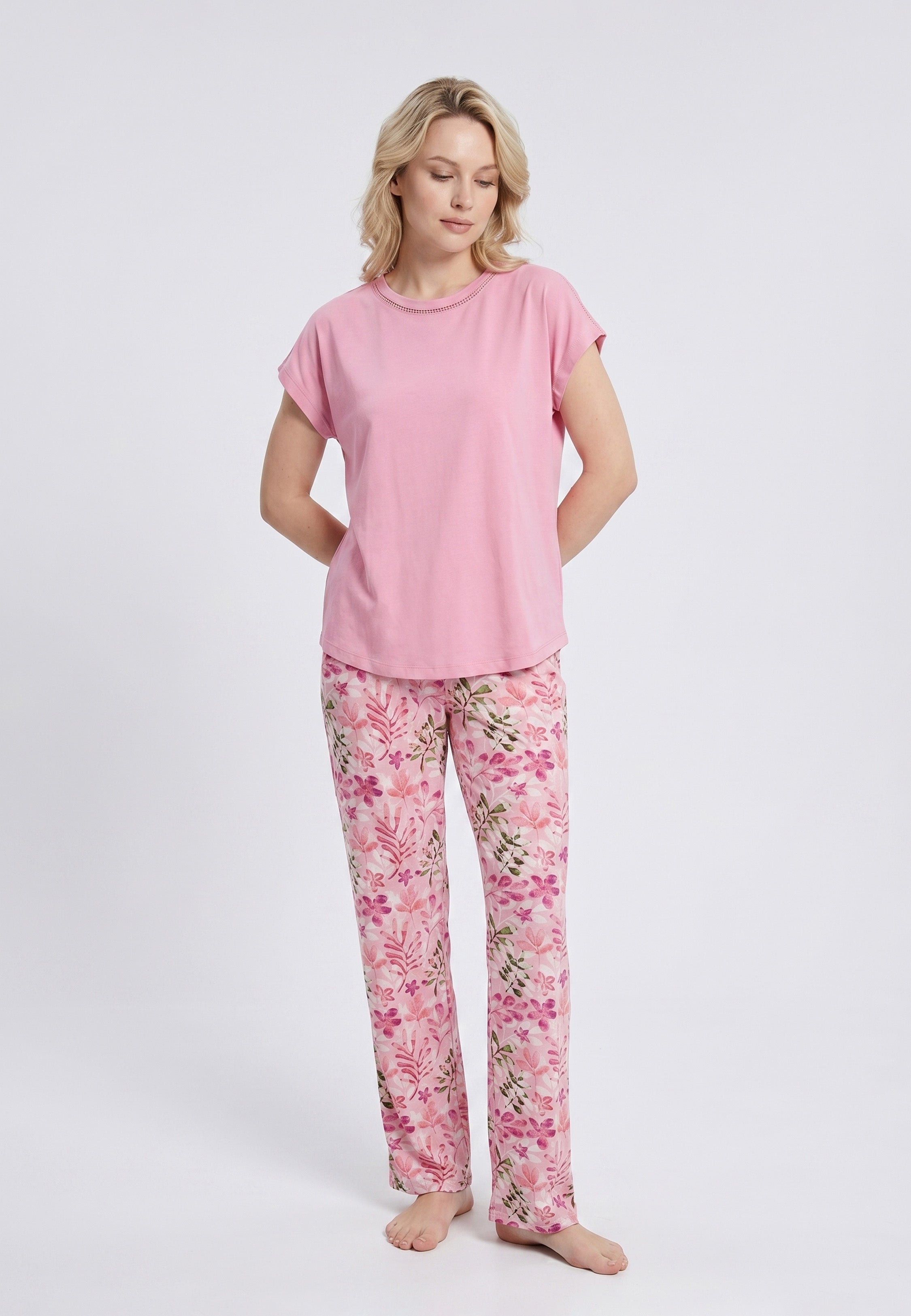 Femme portant un pyjama deux pièces haut uni rose col rond ajouré et pantalon à imprimé floral rose et vert