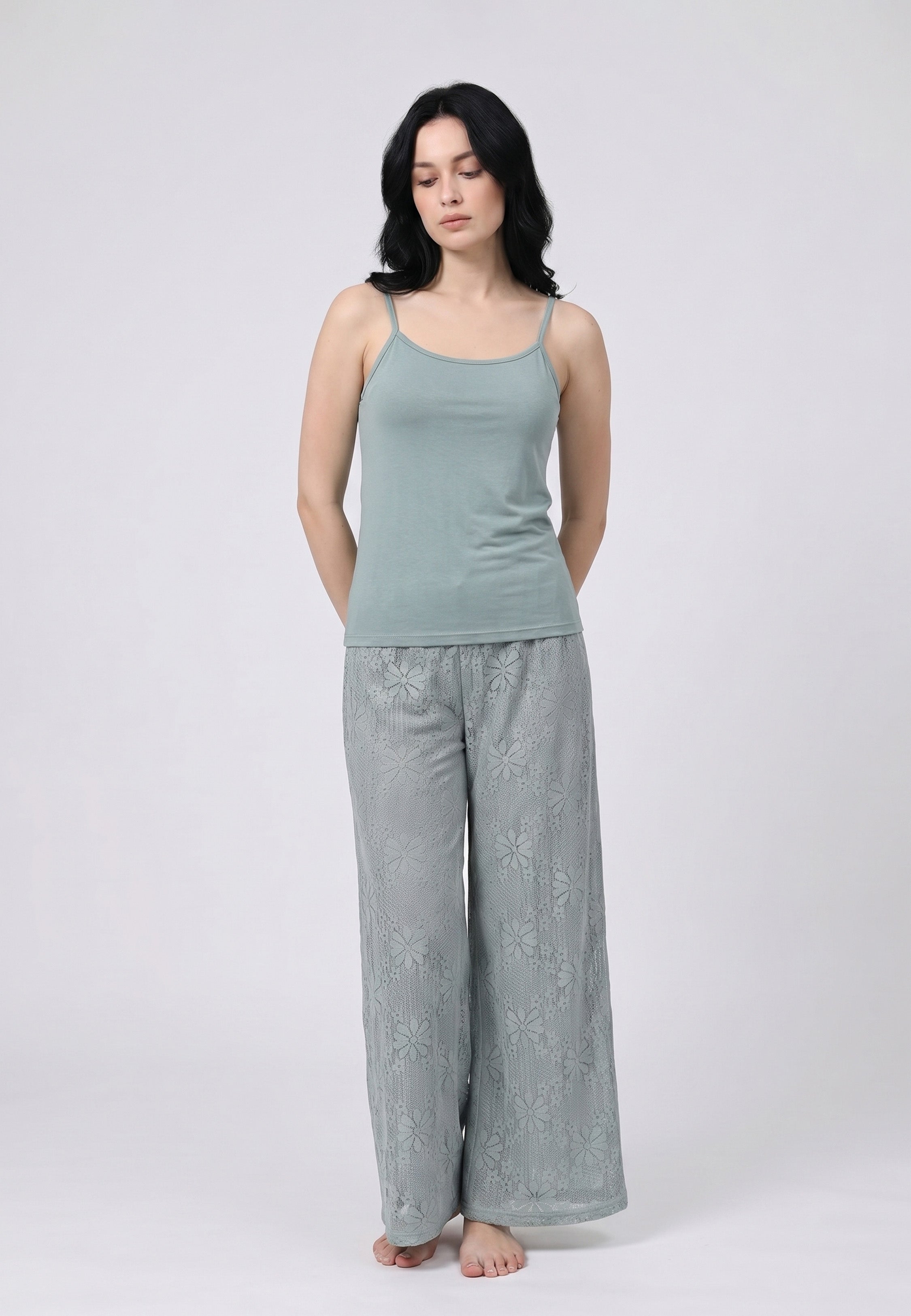 Femme portant un ensemble caraco à bretelles fines vert sauge et pantalon large dentelle florale vert sauge transparente motif marguerites Rosabella