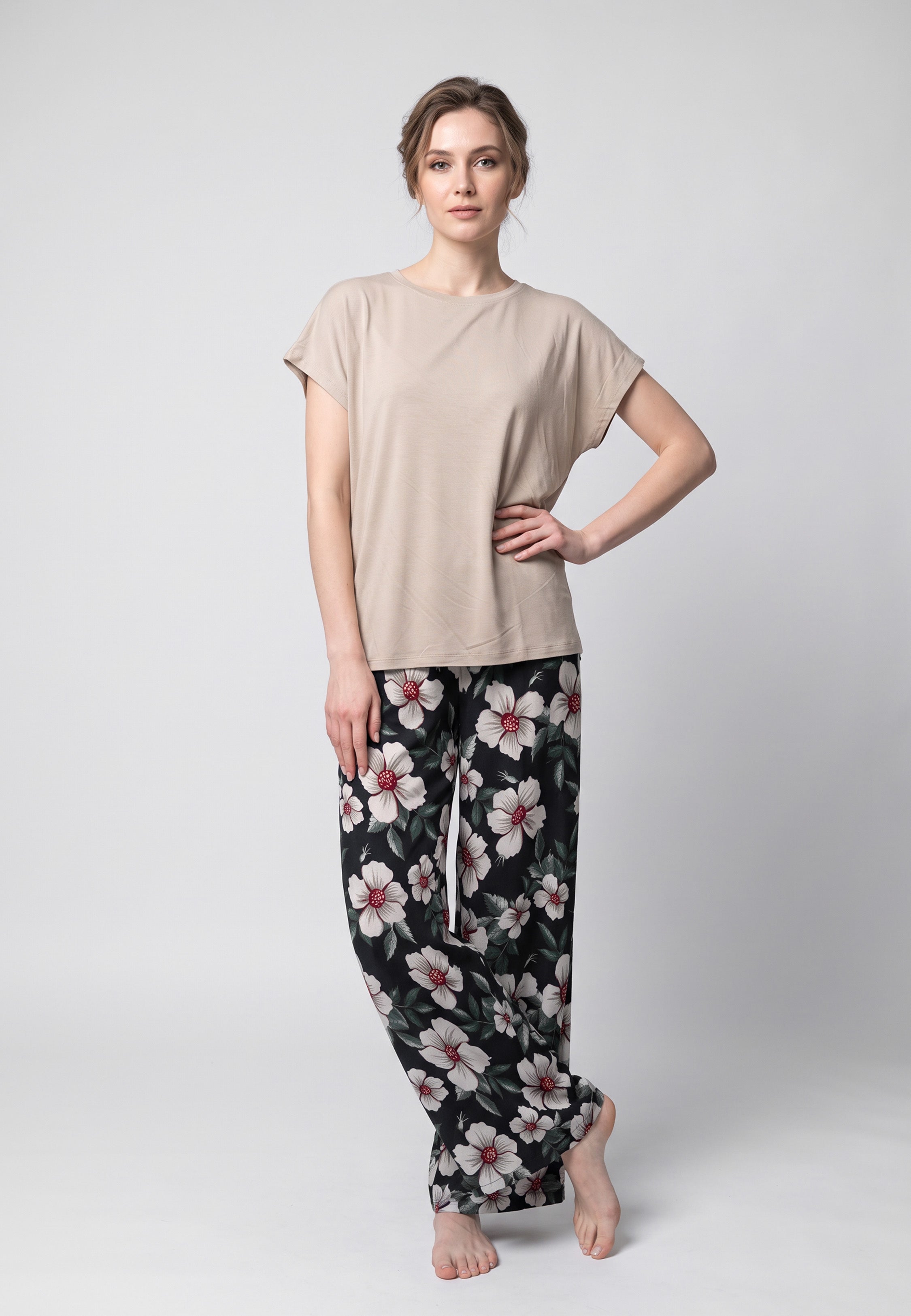 Femme portant un pyjama t-shirt col rond beige et pantalon large noir imprime hibiscus bordeaux Rosabella