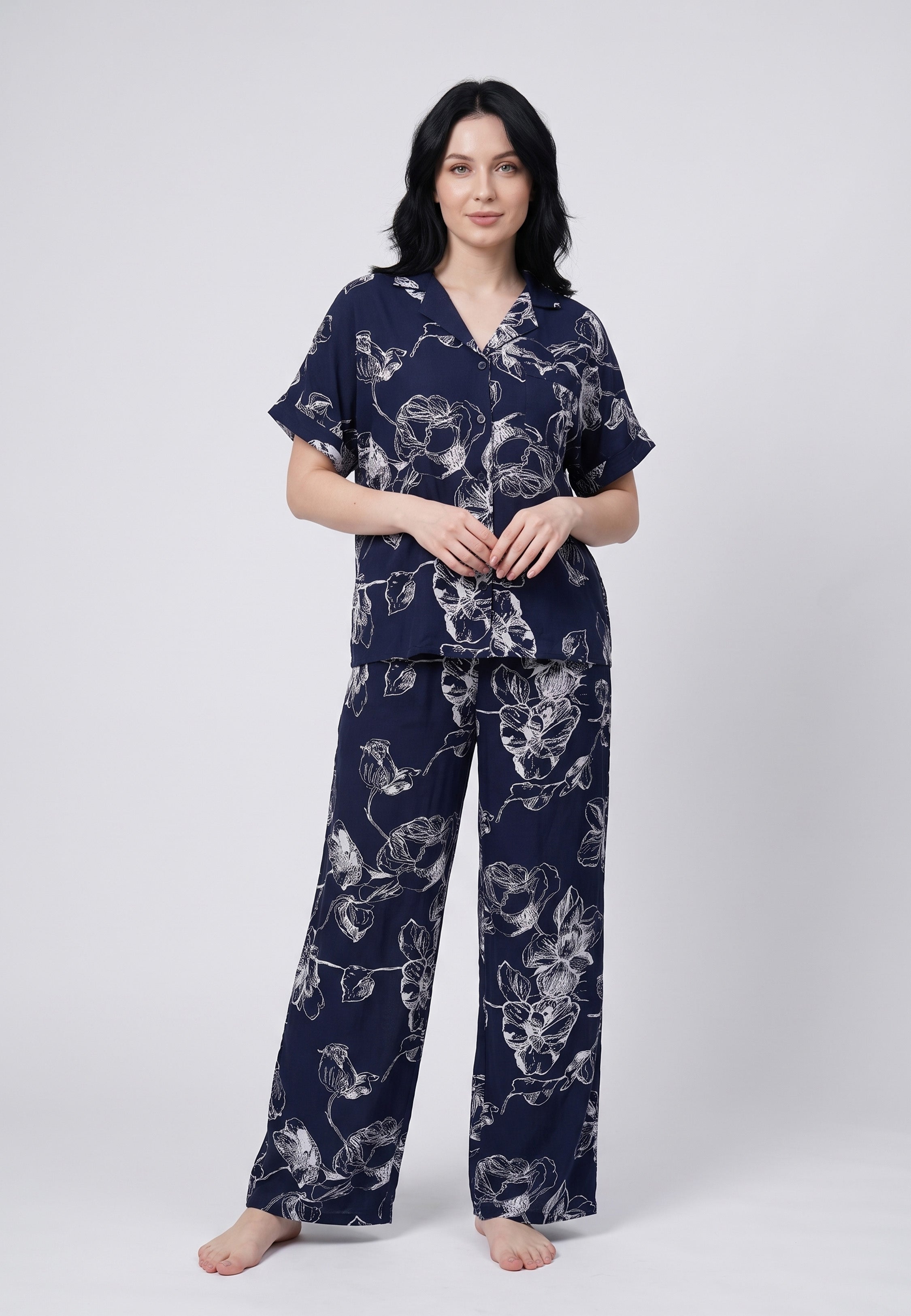 Femme portant un pyjama chemise manches courtes et pantalon large imprimé grandes fleurs écru sur fond marine Rosabella