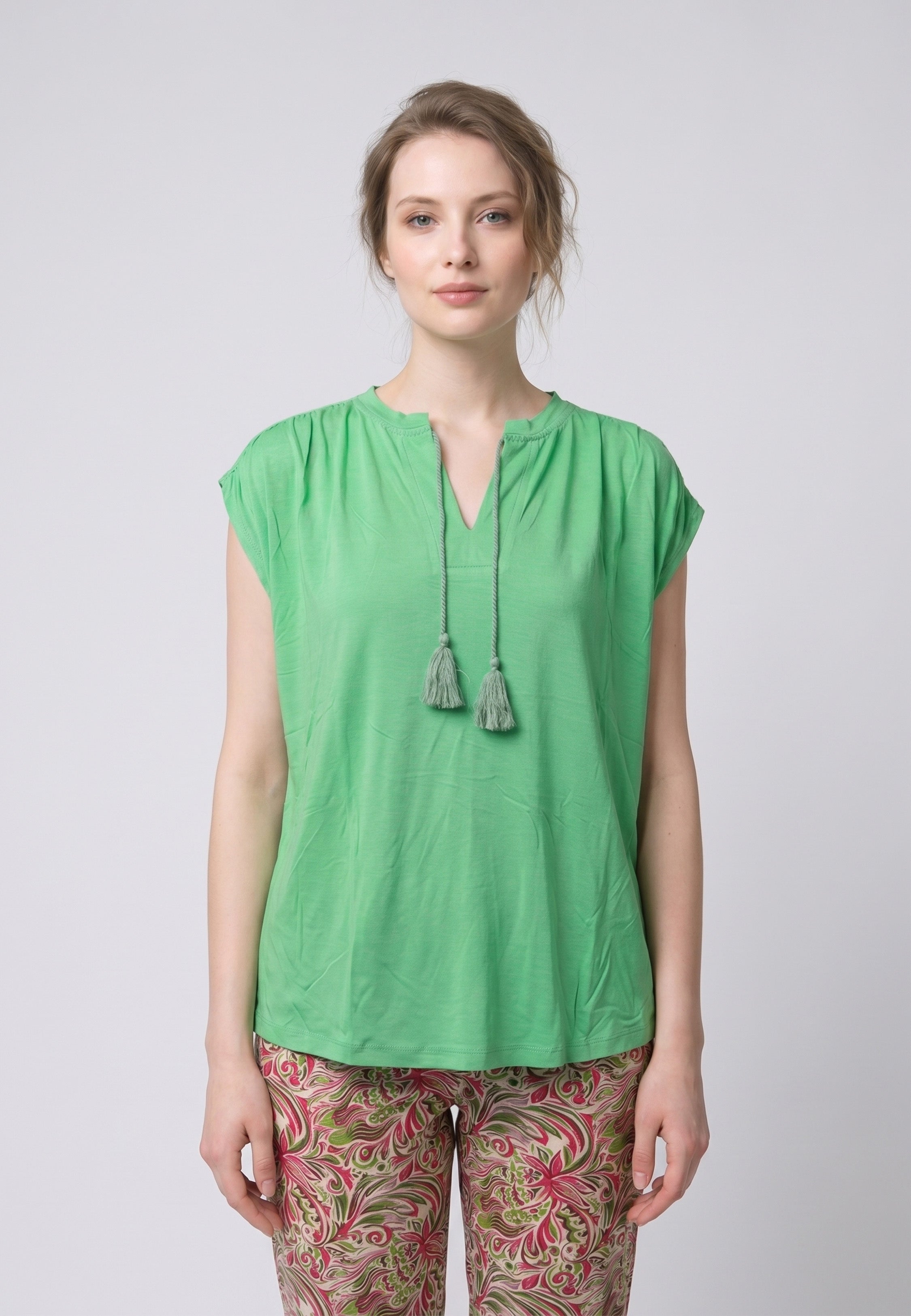 Femme portant un pyjama deux pièces top vert col V avec lacets pompons et pantalon long imprimé ethnique floral multicolore Rosabella Ethnique 2