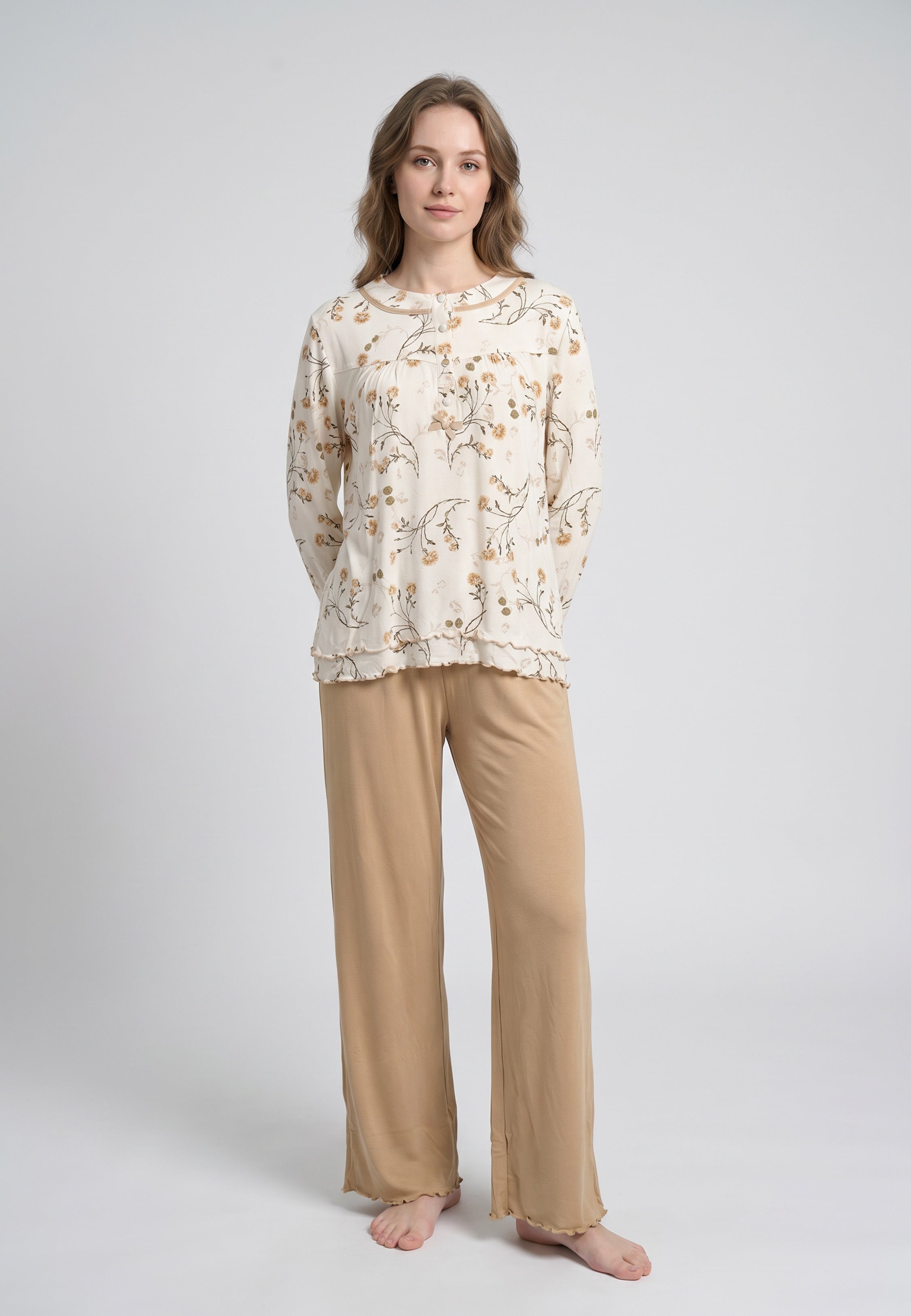 Femme portant un pyjama deux pièces top col rond boutonné manches longues festonné imprimé fleuri fleurs sauvages beige et doré fond crème et pantalon large uni beige festonné Rosabella Soft Bloom
