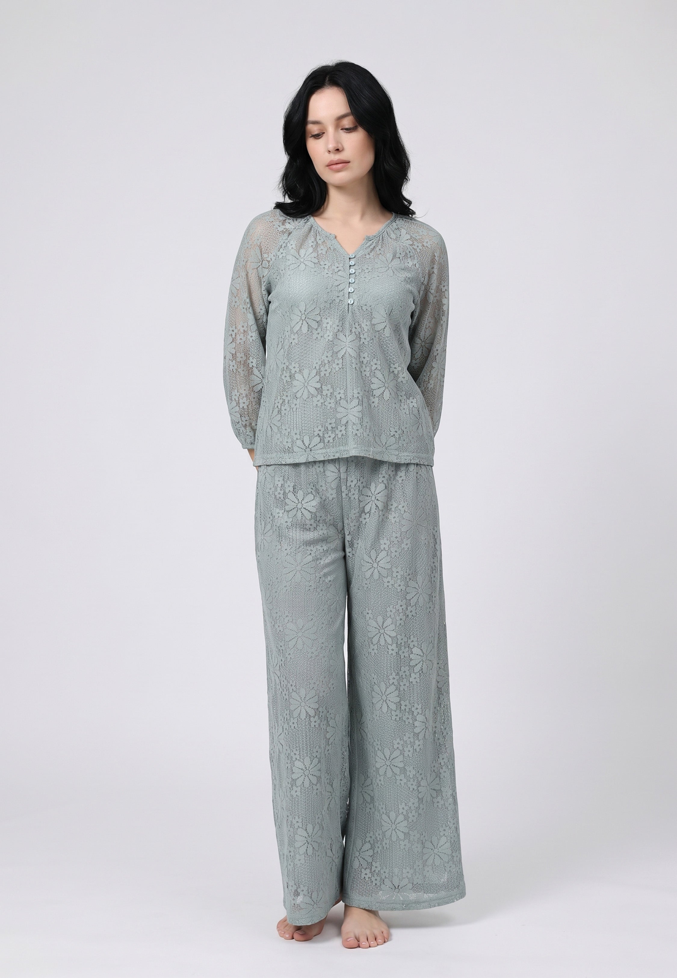 Femme portant un ensemble caraco à bretelles fines vert sauge et pantalon large dentelle florale vert sauge transparente motif marguerites Rosabella