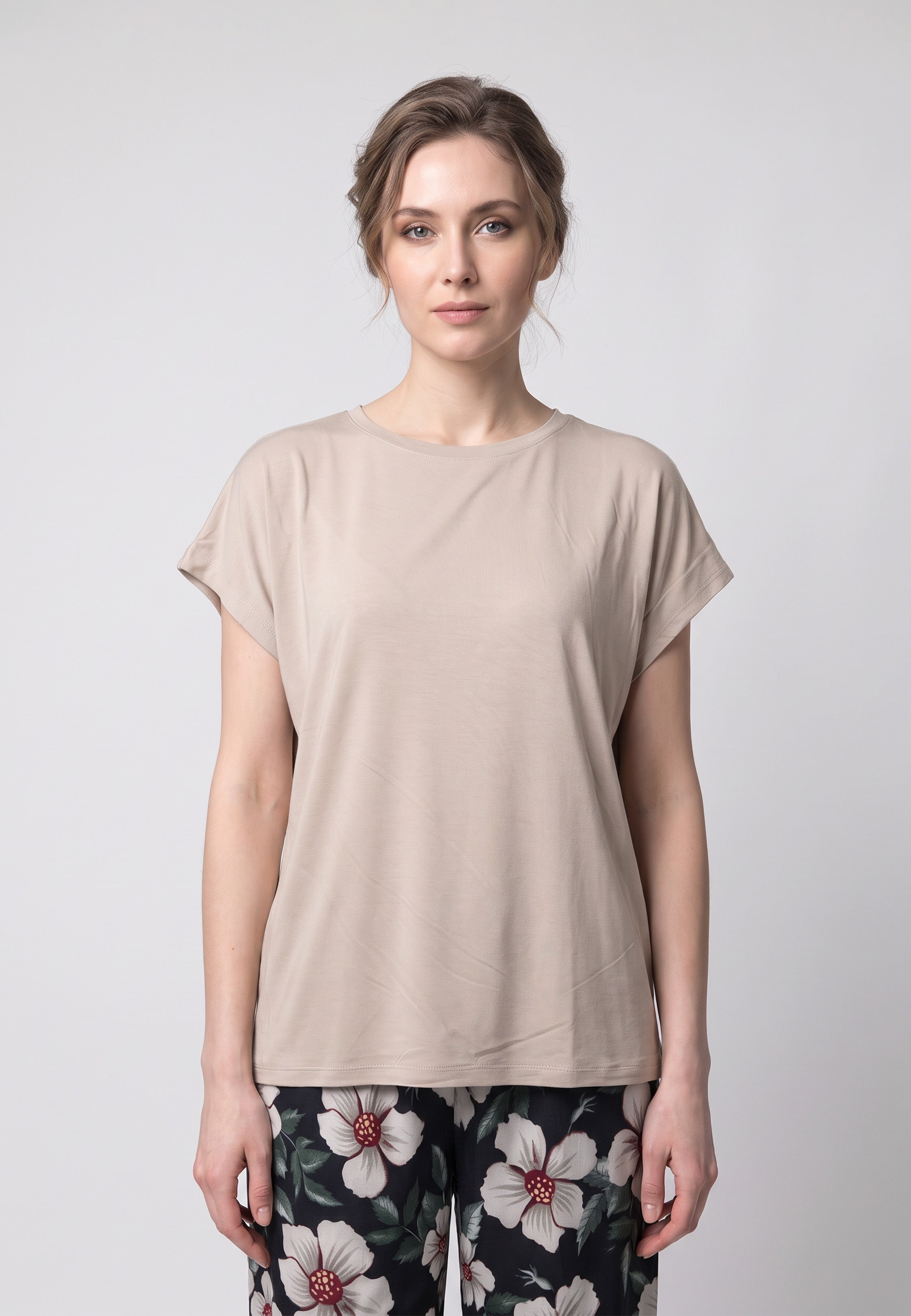 Femme portant un pyjama t-shirt col rond beige et pantalon large noir imprime hibiscus bordeaux Rosabella