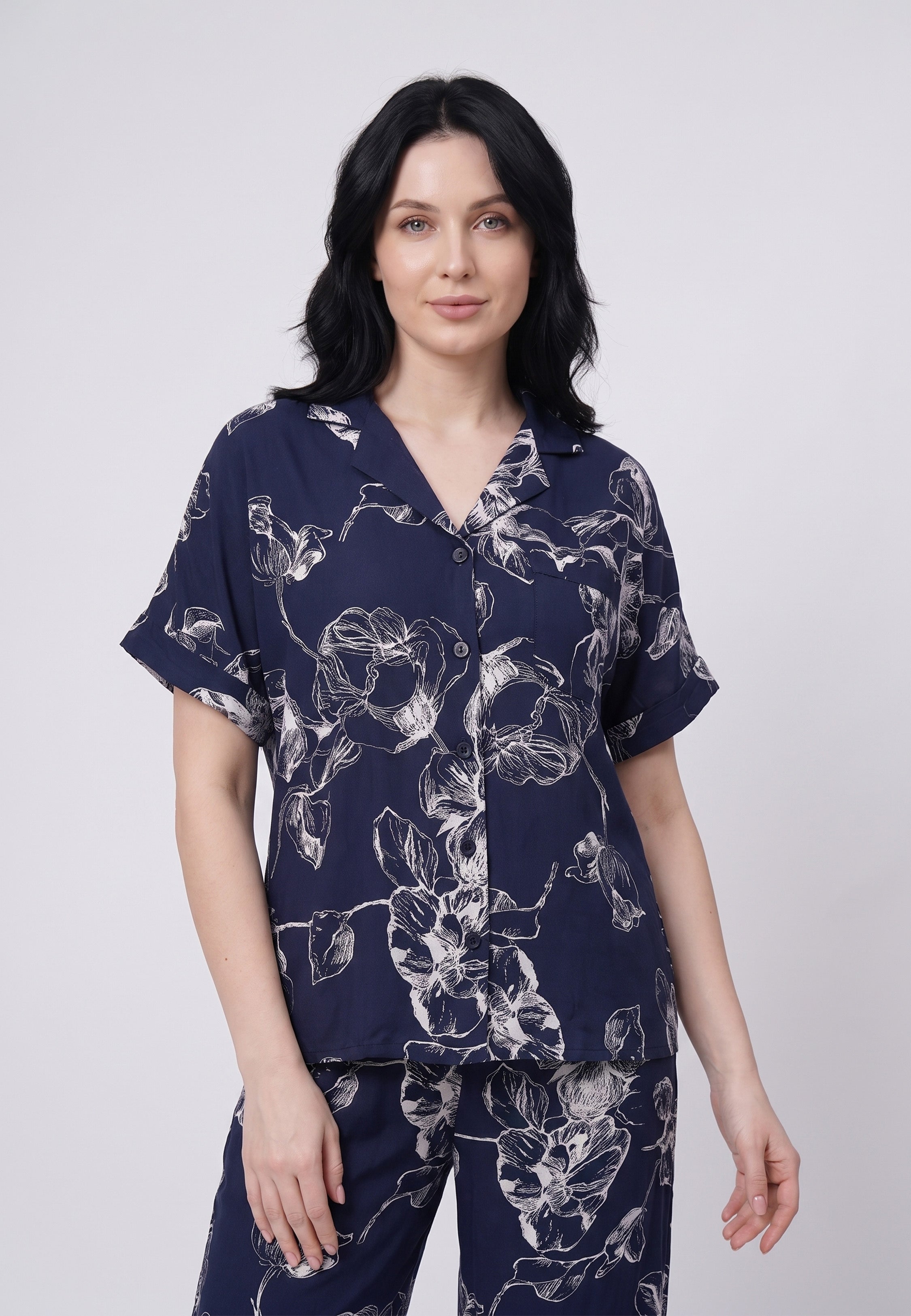Femme portant un pyjama chemise manches courtes et pantalon large imprimé grandes fleurs écru sur fond marine Rosabella