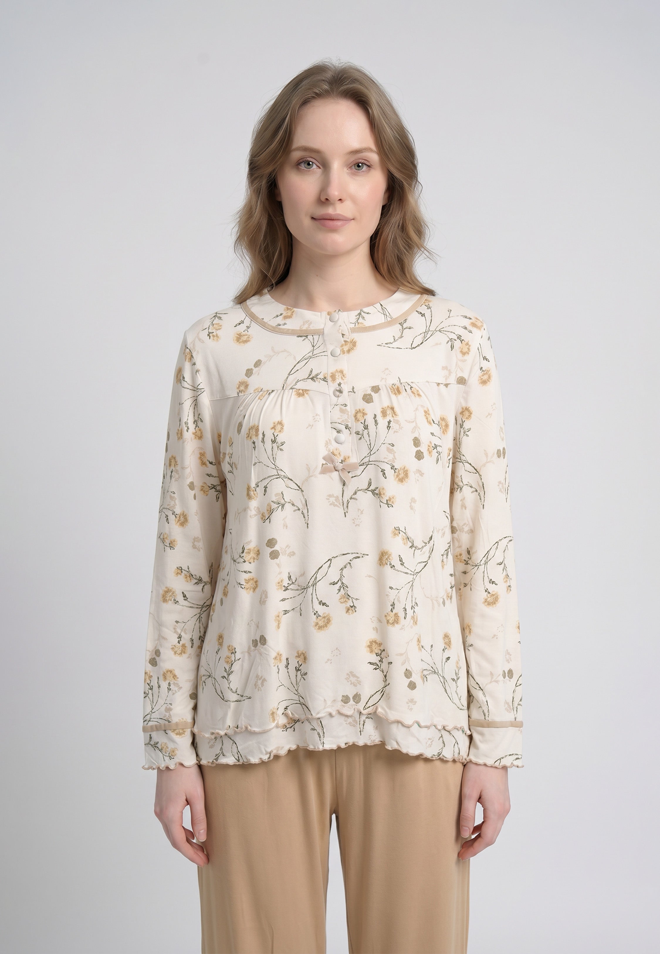 Femme portant un pyjama deux pièces top col rond boutonné manches longues festonné imprimé fleuri fleurs sauvages beige et doré fond crème et pantalon large uni beige festonné Rosabella Soft Bloom