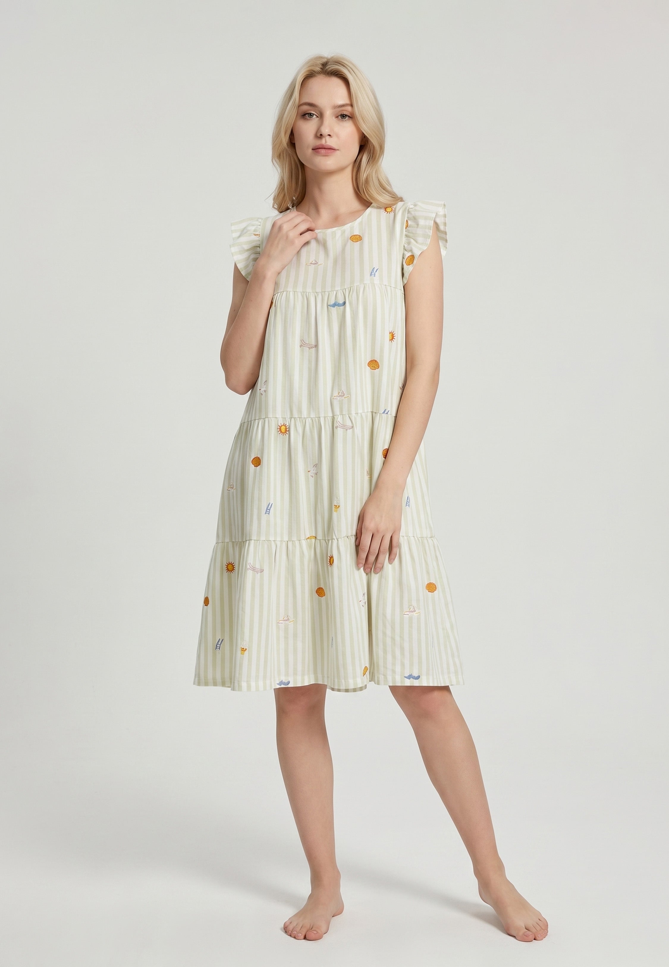 Femme portant une robe mi-longue étagée col rond manches volantées tissu rayé vert amande blanc broderies estivales colorées soleils parasols voiliers coquillages Rosabella
