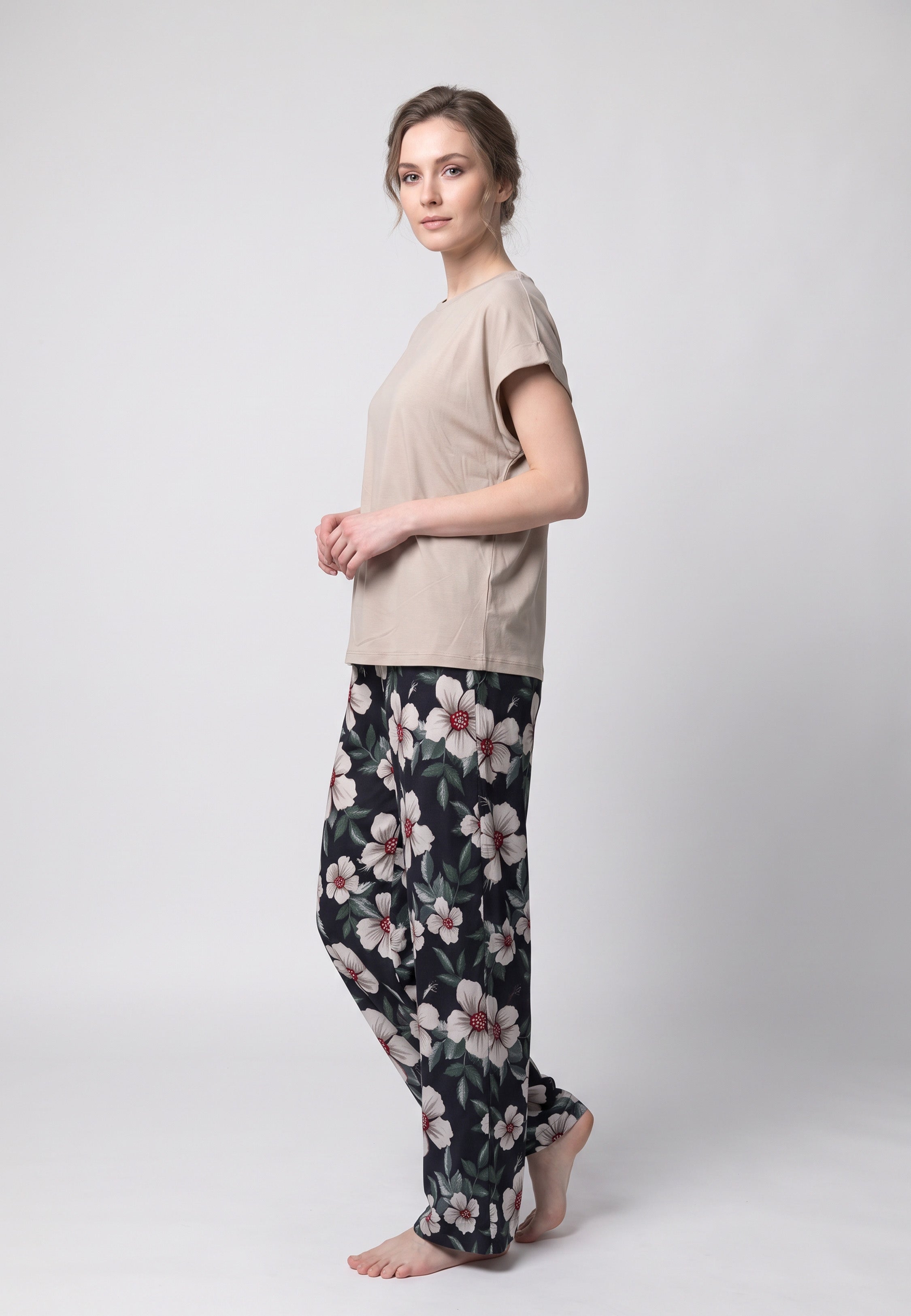 Femme portant un pyjama t-shirt col rond beige et pantalon large noir imprime hibiscus bordeaux Rosabella