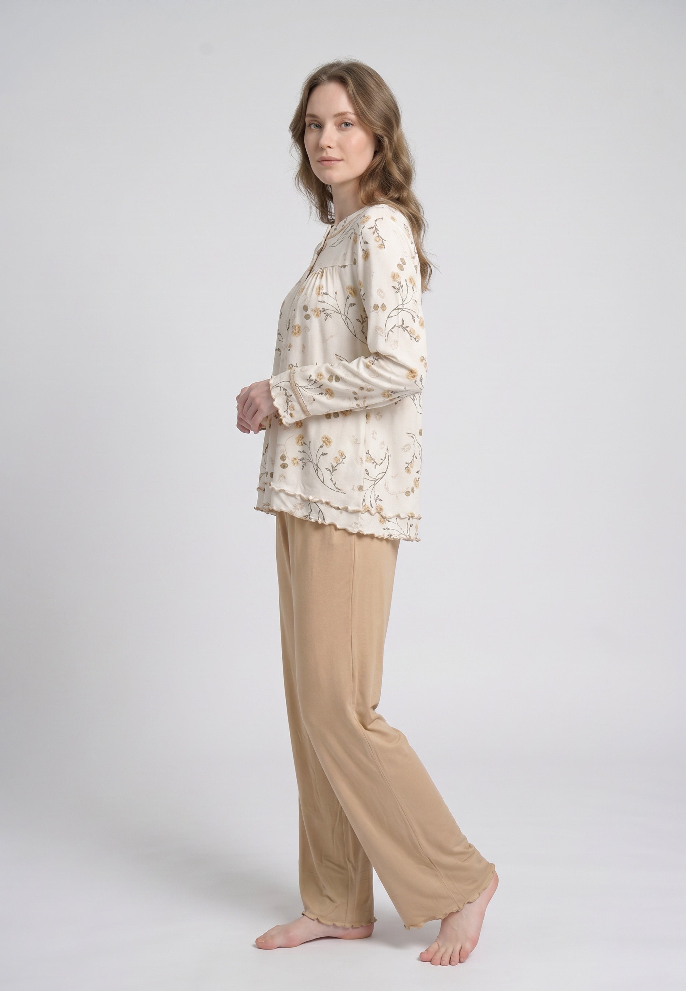 Femme portant un pyjama deux pièces top col rond boutonné manches longues festonné imprimé fleuri fleurs sauvages beige et doré fond crème et pantalon large uni beige festonné Rosabella Soft Bloom