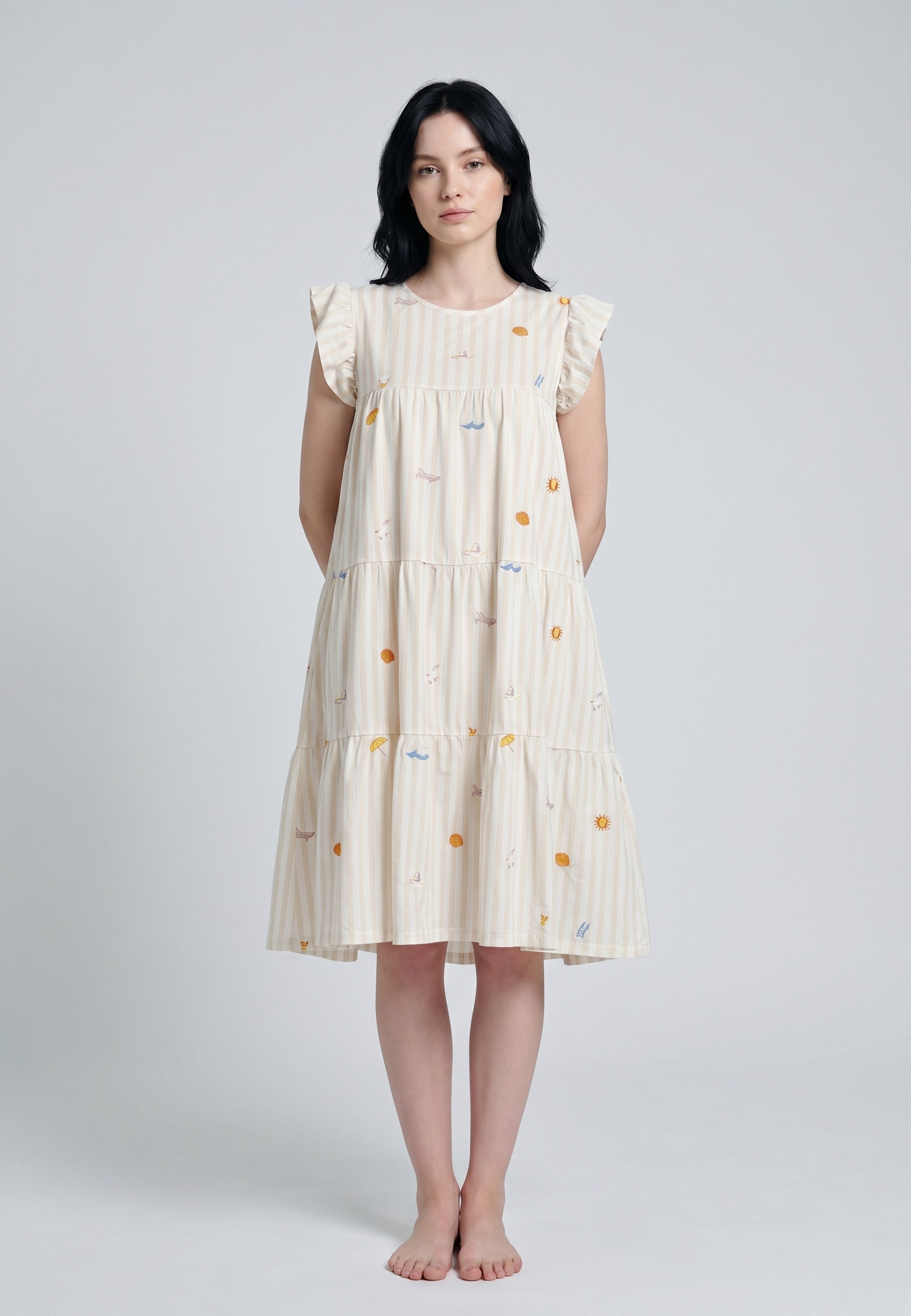 Femme portant une robe mi-longue étagée col rond manches volantées tissu rayé écru beige sable broderies estivales colorées soleils parasols voiliers coquillages Rosabella
