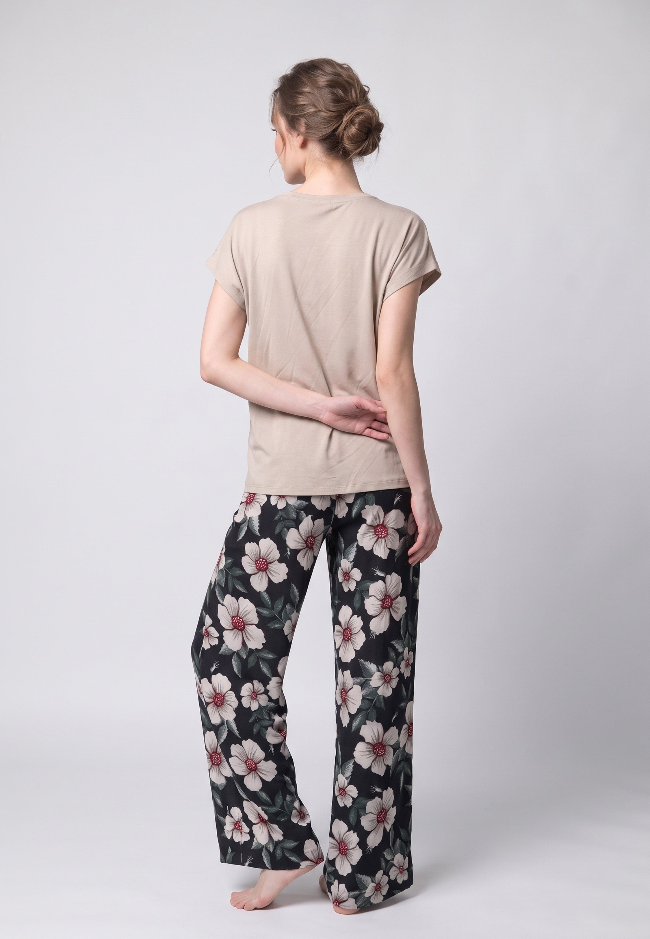 Femme portant un pyjama t-shirt col rond beige et pantalon large noir imprime hibiscus bordeaux Rosabella