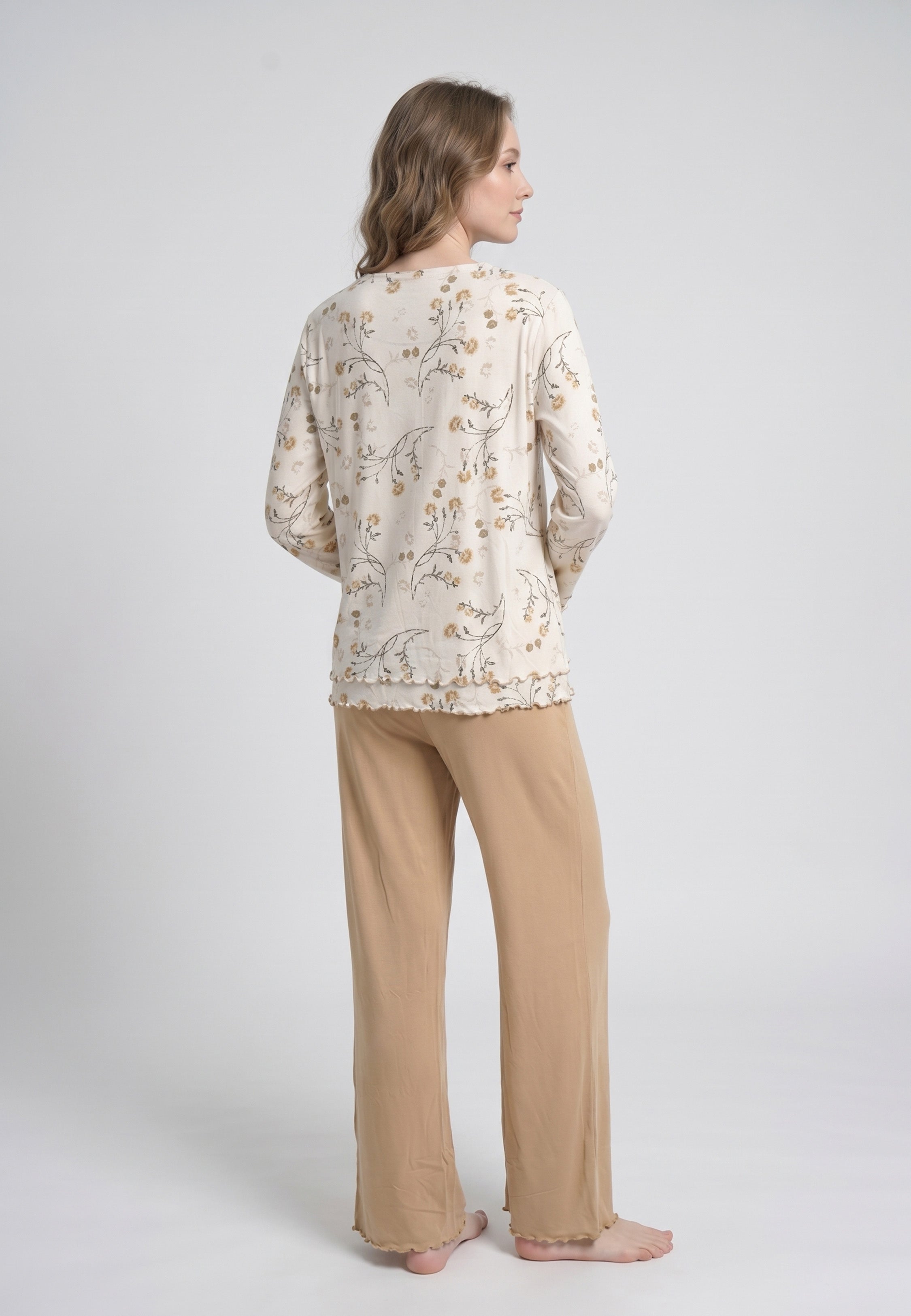 Femme portant un pyjama deux pièces top col rond boutonné manches longues festonné imprimé fleuri fleurs sauvages beige et doré fond crème et pantalon large uni beige festonné Rosabella Soft Bloom