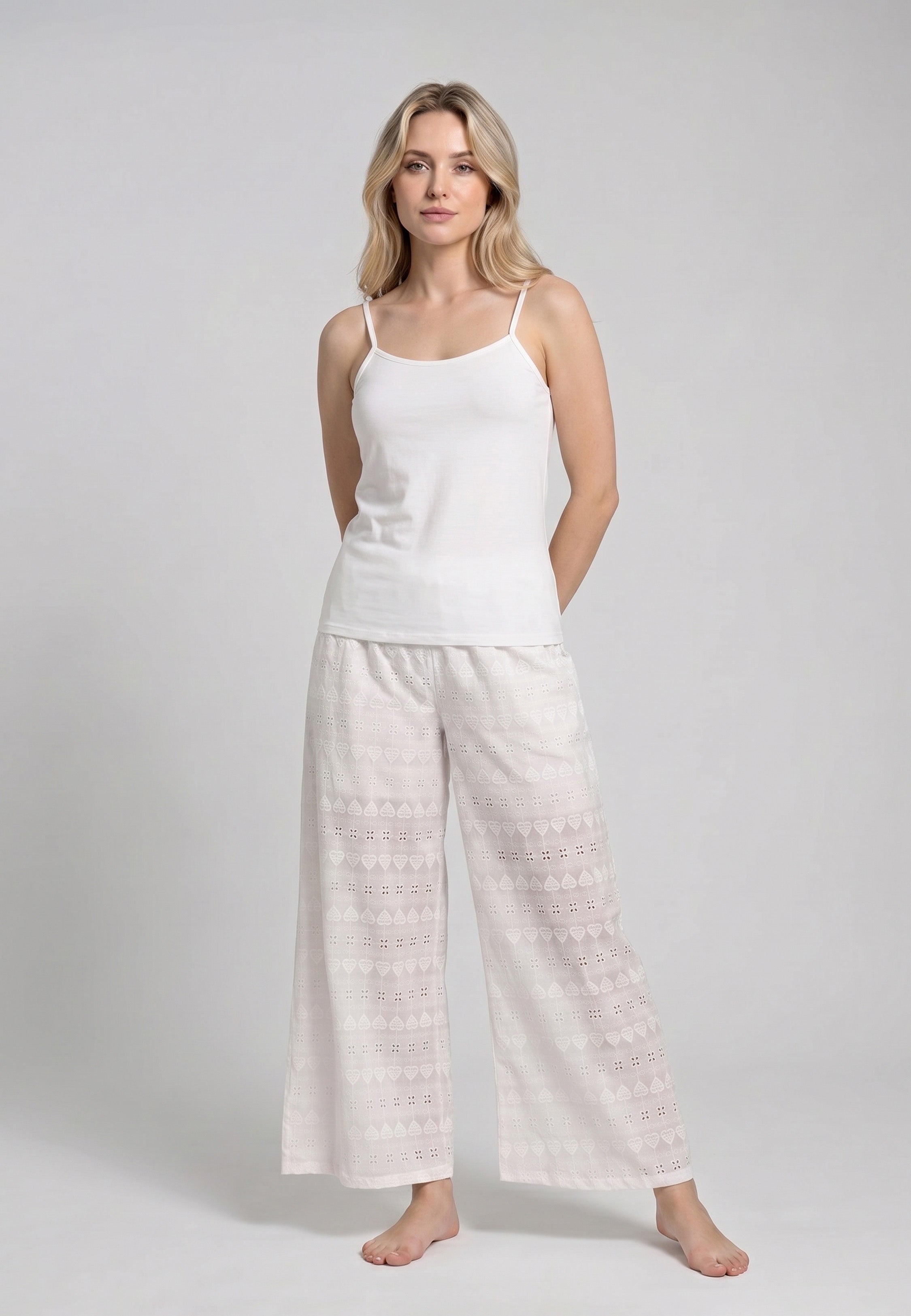 Femme portant un ensemble caraco bretelles fines coton blanc et pantalon large broderie anglaise blanche motifs géométriques ajourés Rosabella